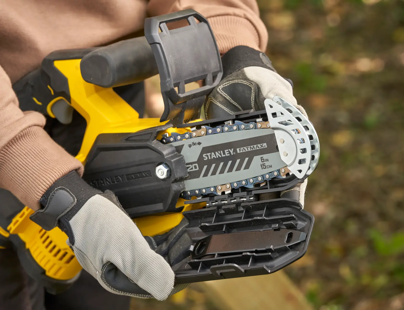 STANLEY SFMCPS415D1 FatMax motosega in primo piano, barra della catena e guanti protettivi all'aperto.