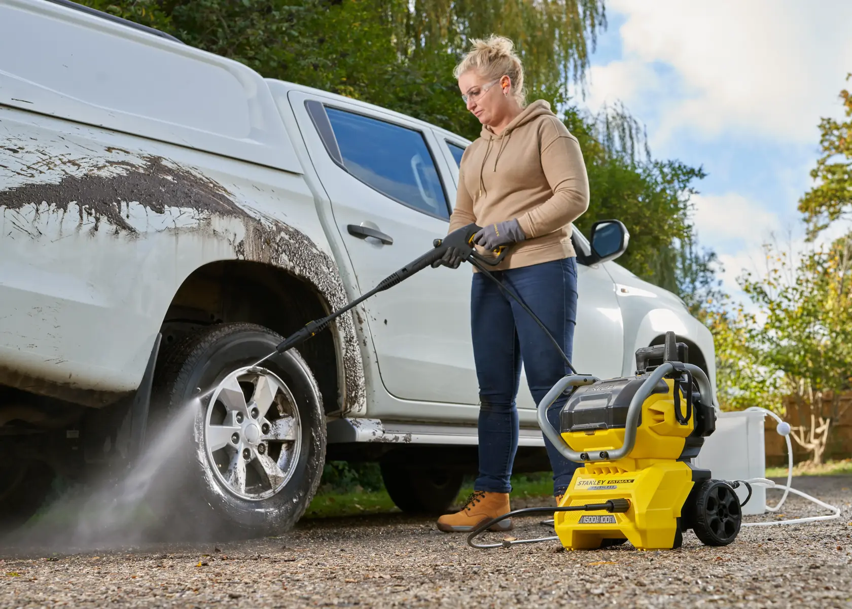 Idropulitrice STANLEY SFMCPW1500B che pulisce la ruota di un veicolo bianco sporco all'aperto.