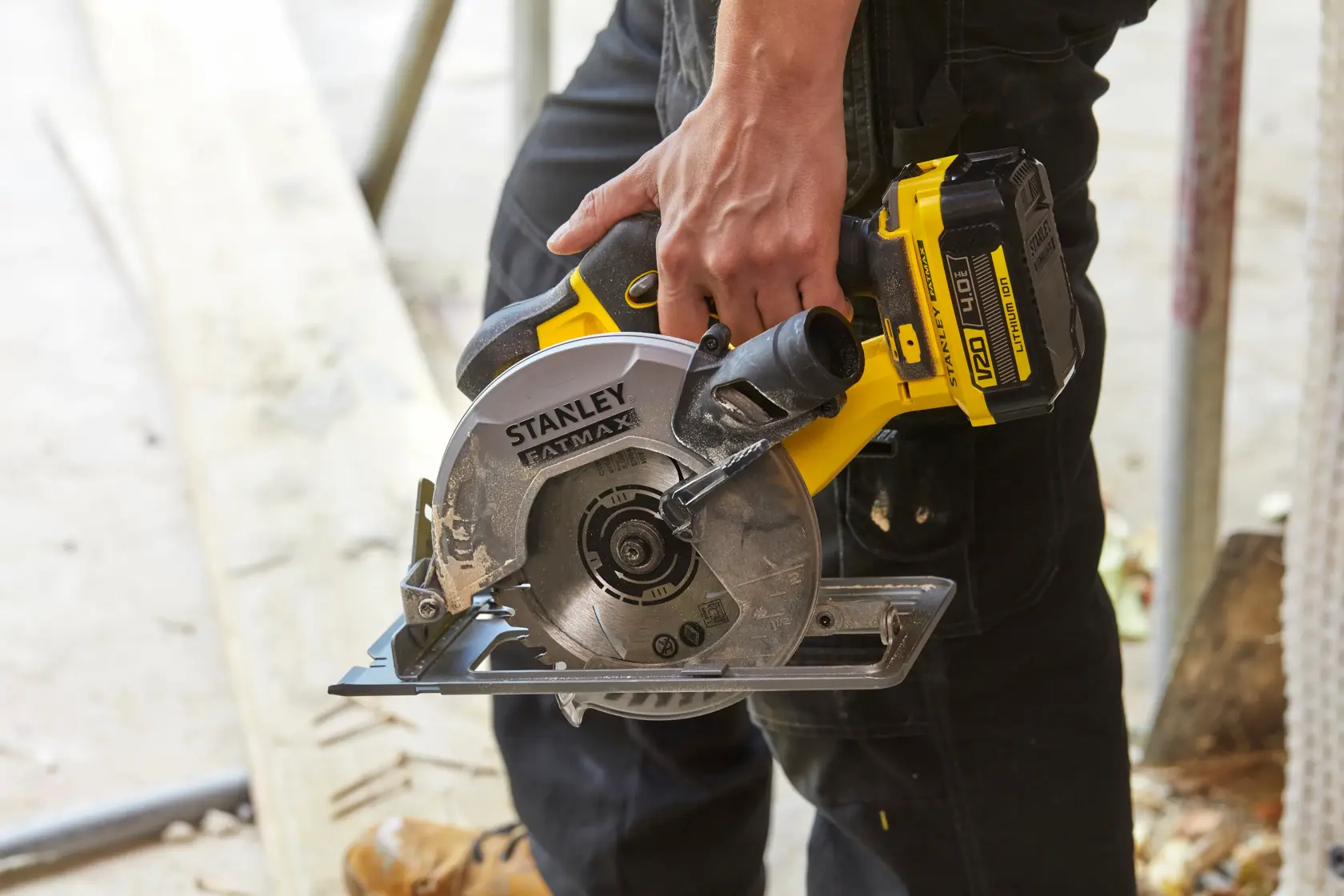 STANLEY SFMCS500B sega circolare senza fili tenuta da persona, design giallo e nero, contesto cantiere.