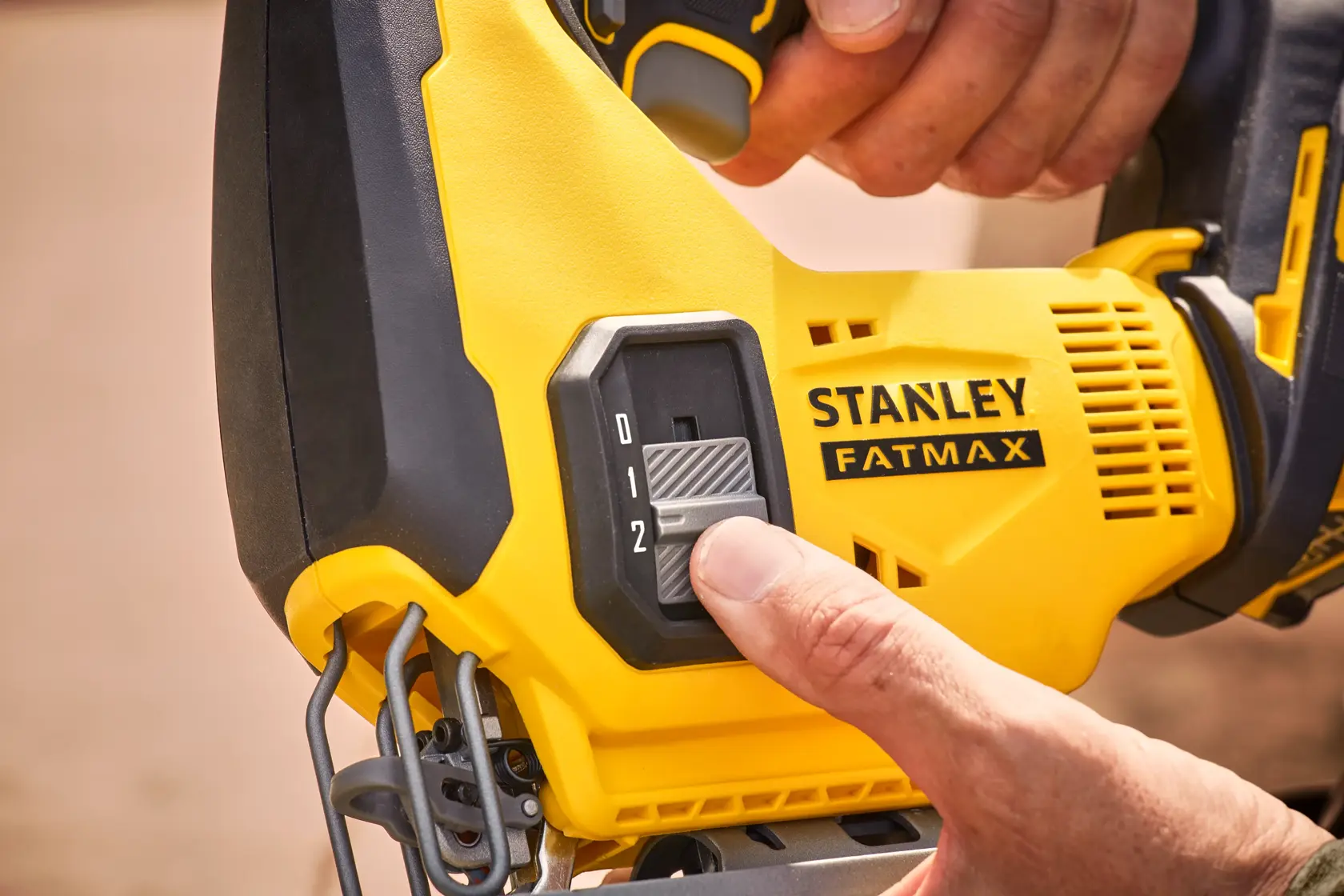 STANLEY SFMCS600B seghetto alternativo in primo piano, mano che regola l’interruttore di velocità su corpo giallo e nero.