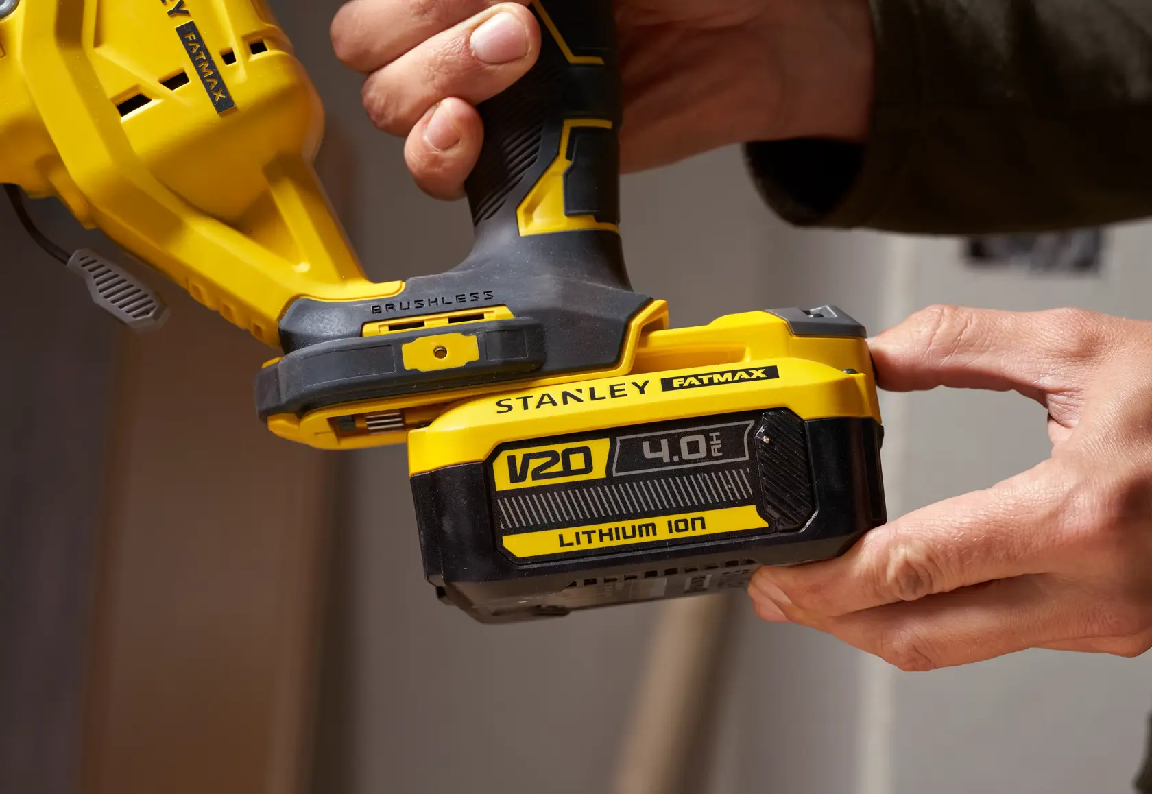 Foto del seghetto STANLEY SFMCS650B 18V FATMAX V20 brushless tenuto in mano, primo piano sulla batteria V20 Lithium Ion.