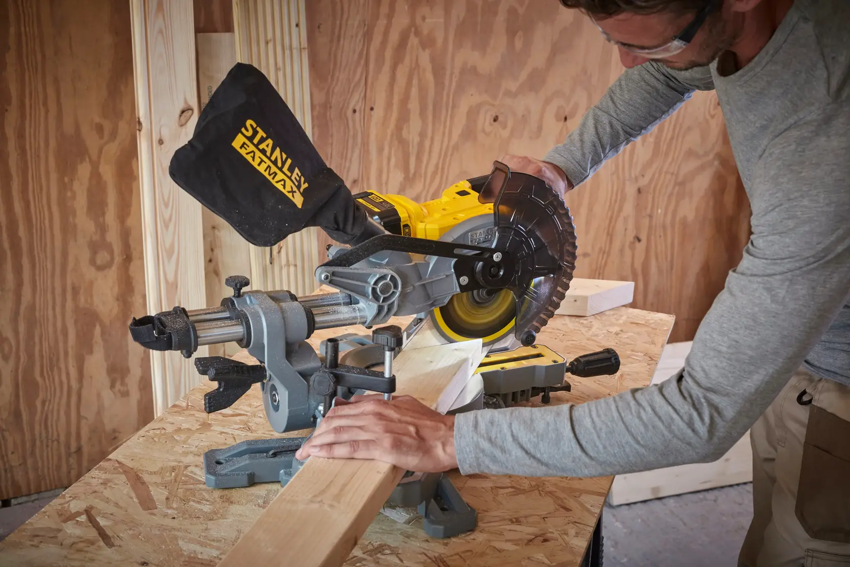 Troncatrice STANLEY SFMCS701M1 in uso per tagliare legno su banco da lavoro, sacco raccogli polvere, ambiente interno.