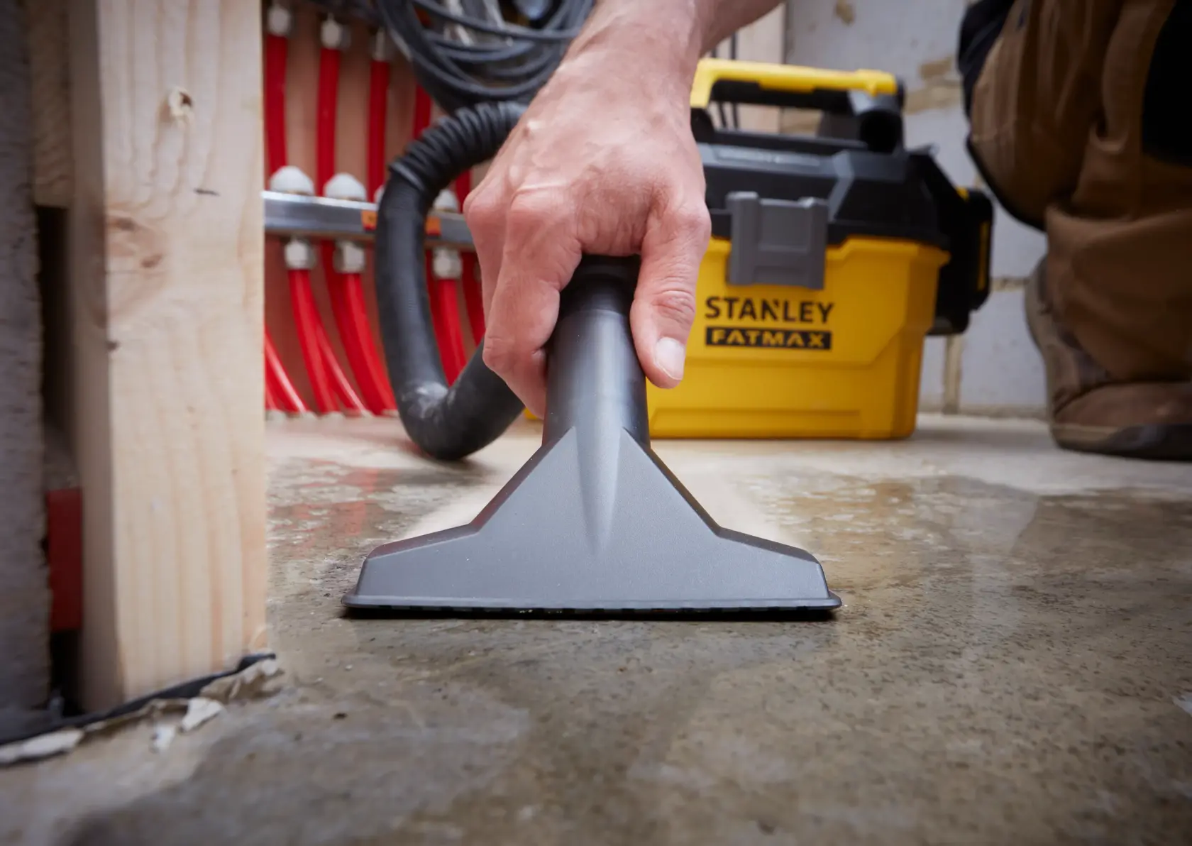 Aspirapolvere/liquidi STANLEY SFMCV002B usato su pavimento bagnato, primo piano della bocchetta e unità gialla.