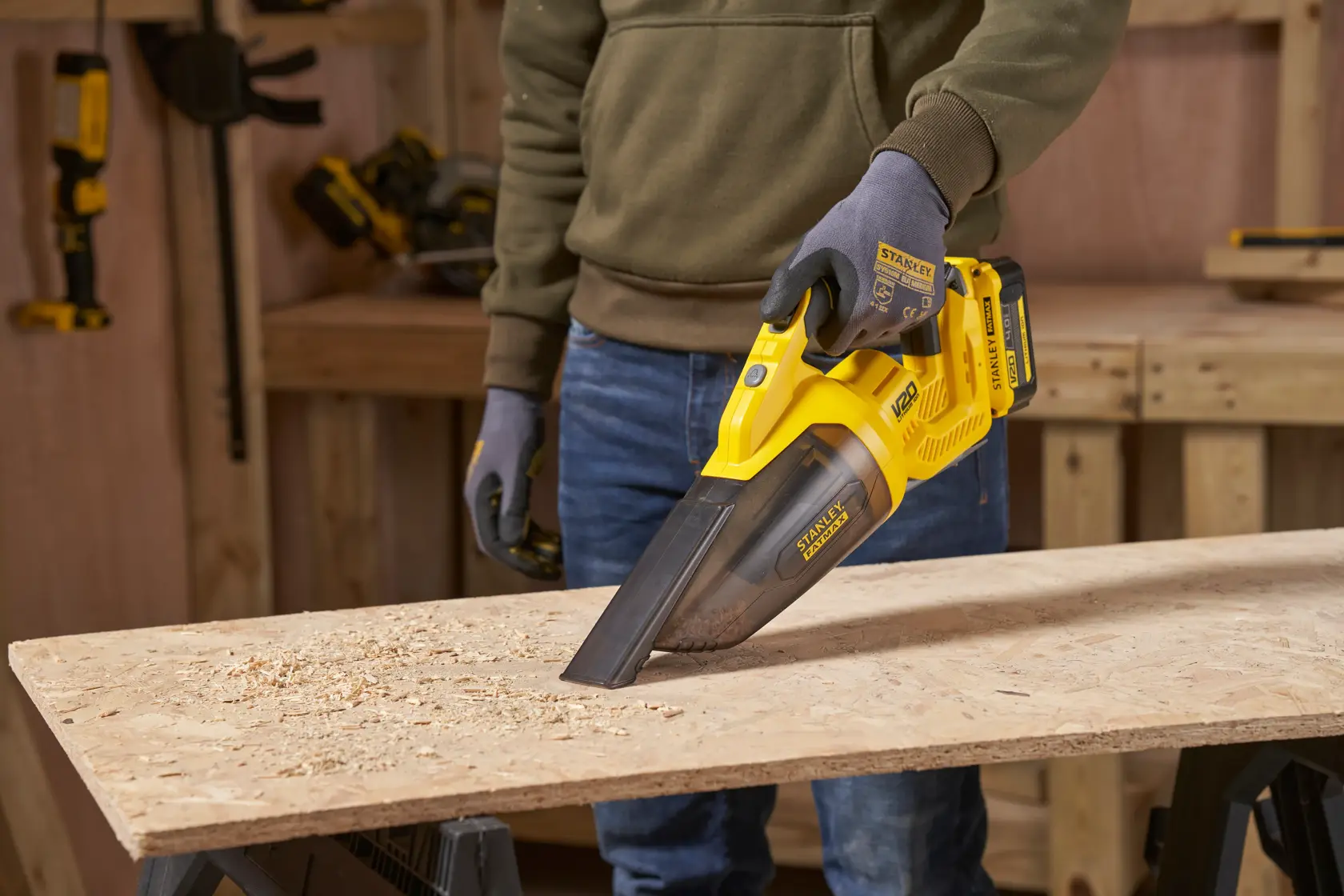 STANLEY SFMCVH001B aspirapolvere portatile usato per rimuovere la segatura da una tavola di legno in officina.