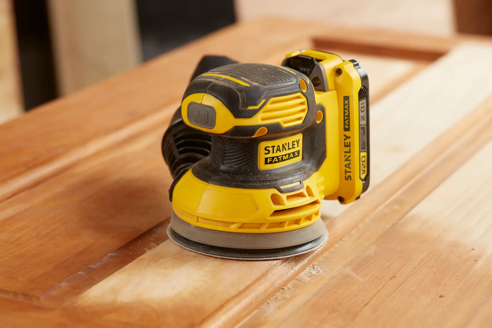 STANLEY SFMCW220B levigatrice senza fili su superficie di legno, gialla e nera, angolo laterale ravvicinato.