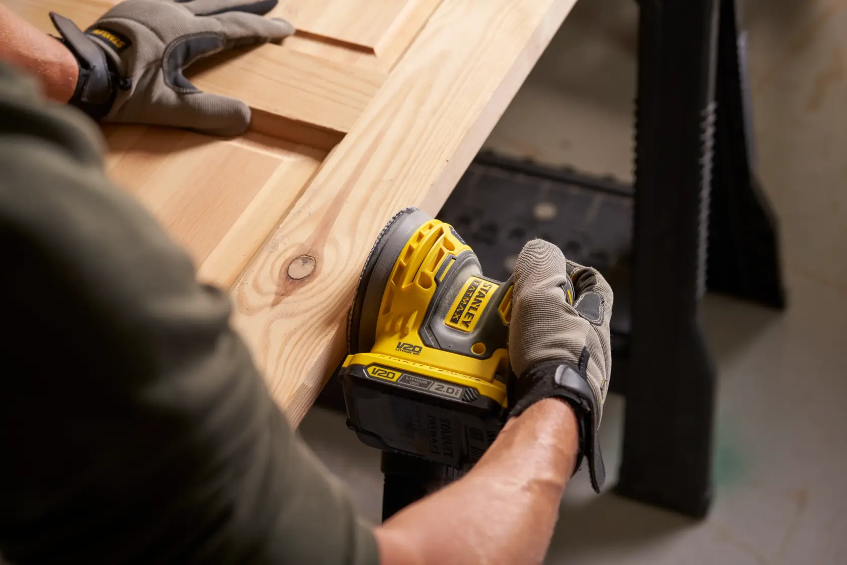 Foto della levigatrice cordless STANLEY SFMCW220B usata su una superficie in legno, vista ravvicinata.