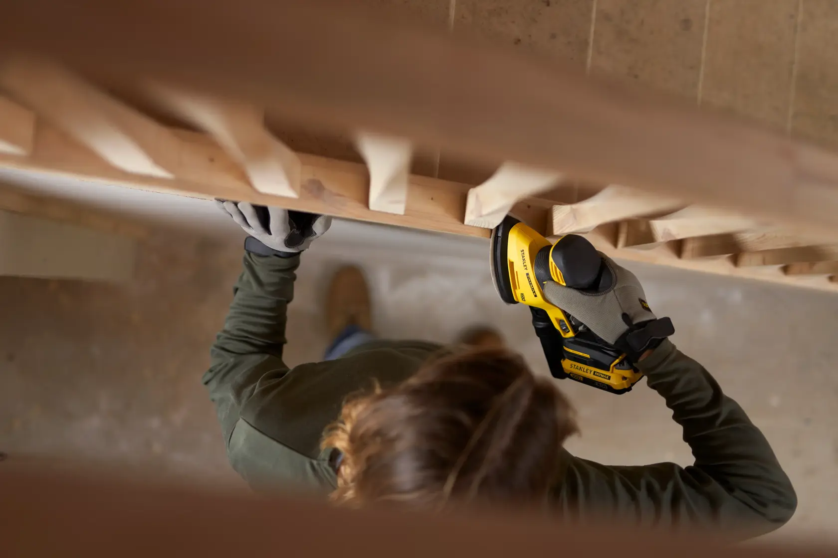 Foto di una persona che usa la levigatrice senza filo STANLEY SFMCW221B su corrimano in legno.