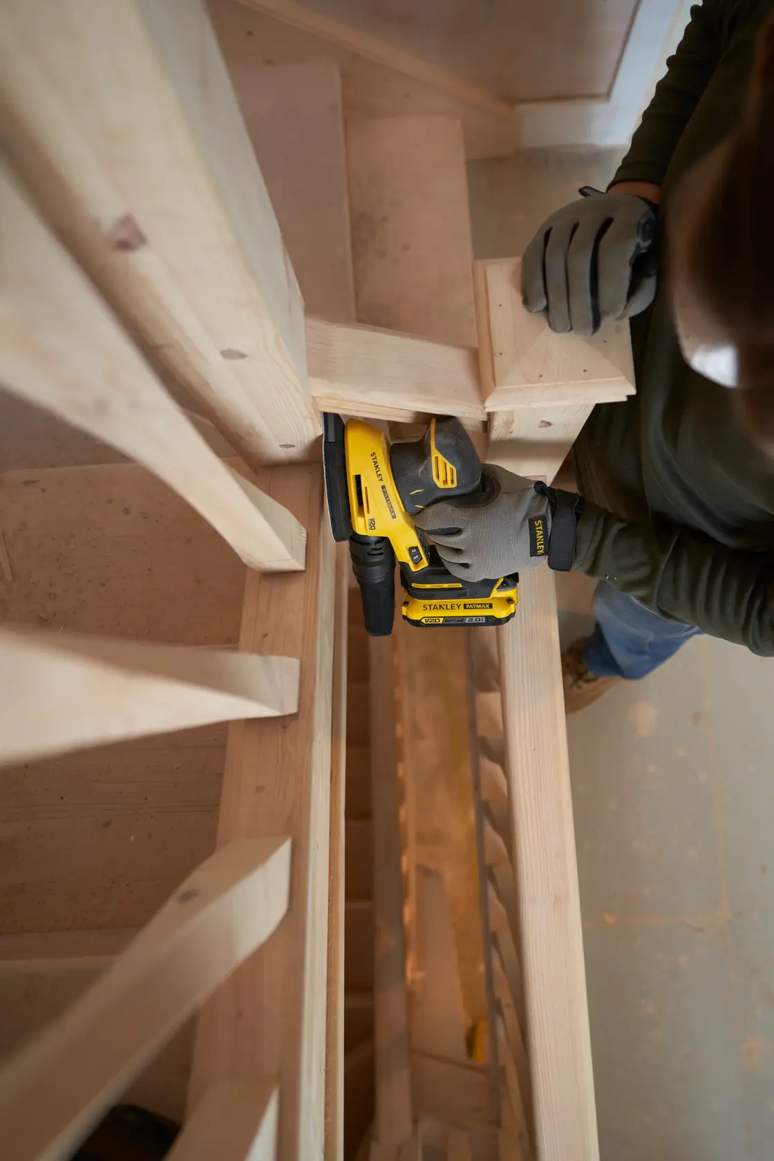 STANLEY SFMCW221B levigatrice usata su scale in legno, angolo ravvicinato, operatore con guanti.