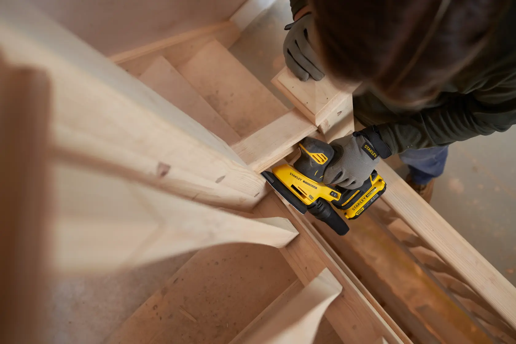 STANLEY SFMCW221D1S levigatrice senza fili usata su scale in legno, vista dall'alto.