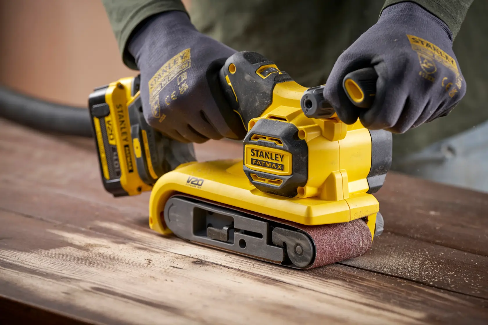 Stanley SFMCW223B-XJ levigatrice a nastro senza fili su legno, angolo ravvicinato, design giallo e nero.
