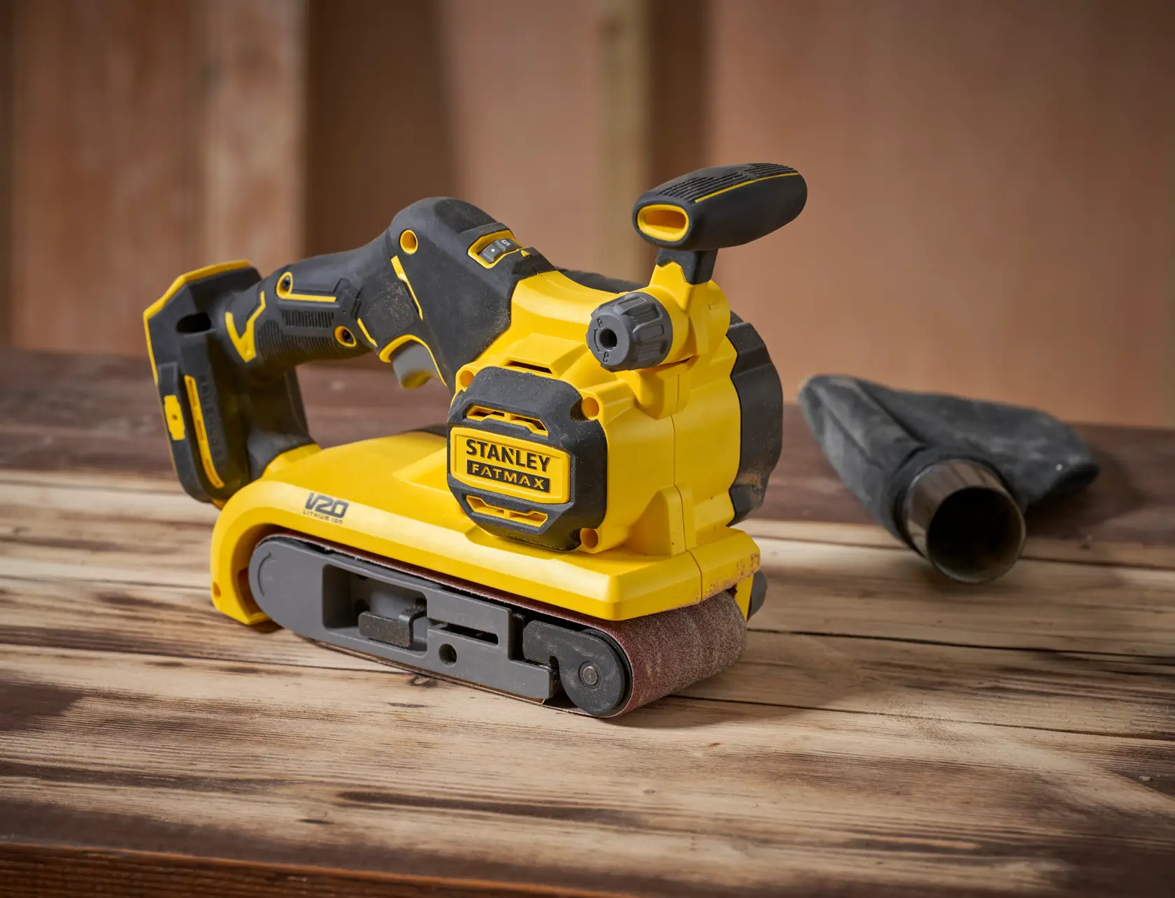 STANLEY SFMCW223B-XJ levigatrice a nastro, gialla e nera, angolo laterale, su superficie in legno.