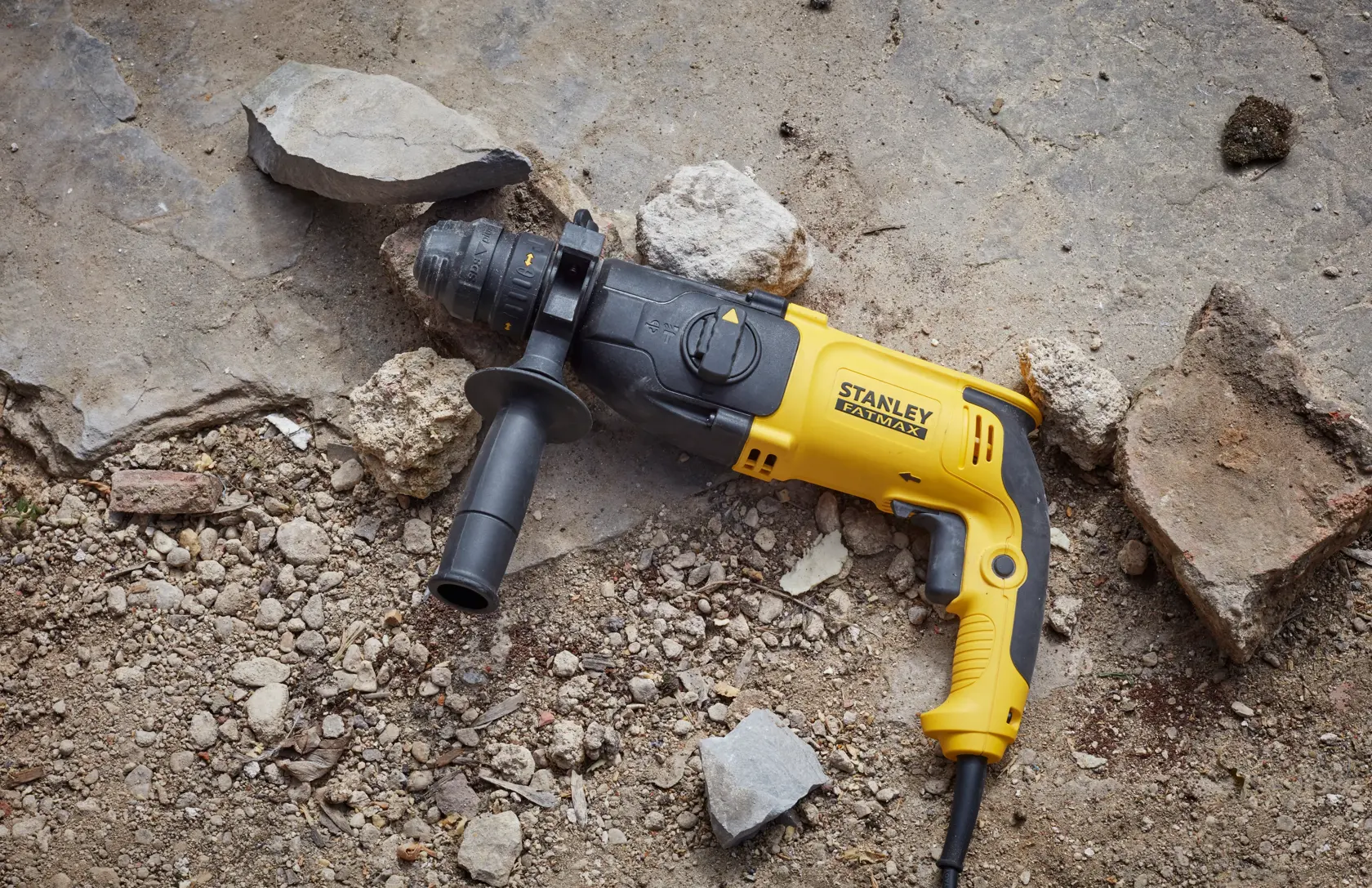 STANLEY SFMEH210K-QS trapano a percussione con cavo giallo e nero su terreno roccioso.