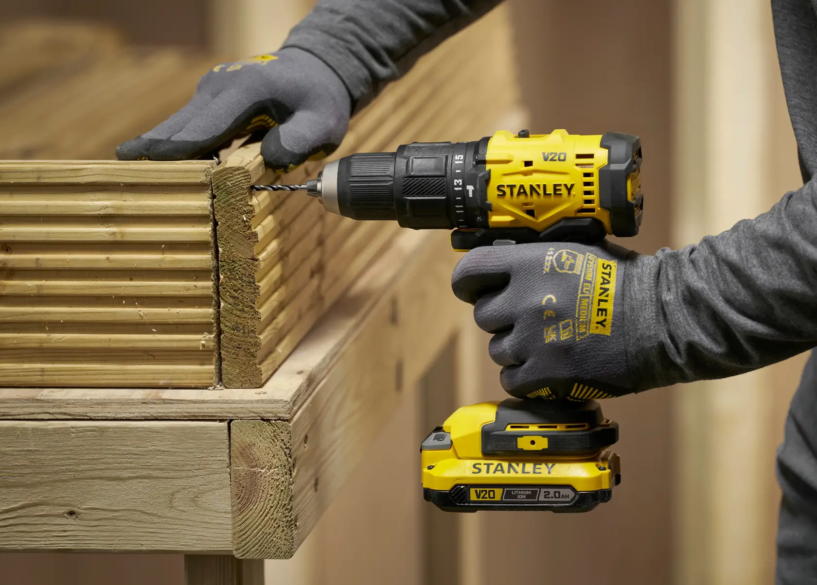 Trapano Stanley su legno, STA56001-QZ e STA56001 SKU visibili, persona con guanti.