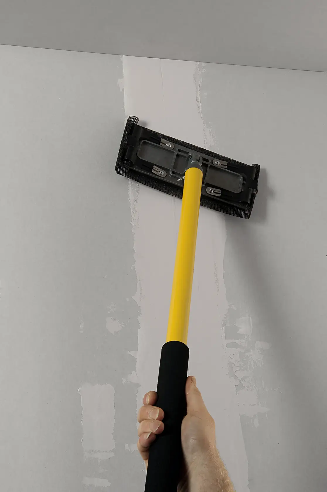 STANLEY STHT0-05928 levigatrice per cartongesso con manico giallo utilizzata sul soffitto, fotografia ravvicinata.
