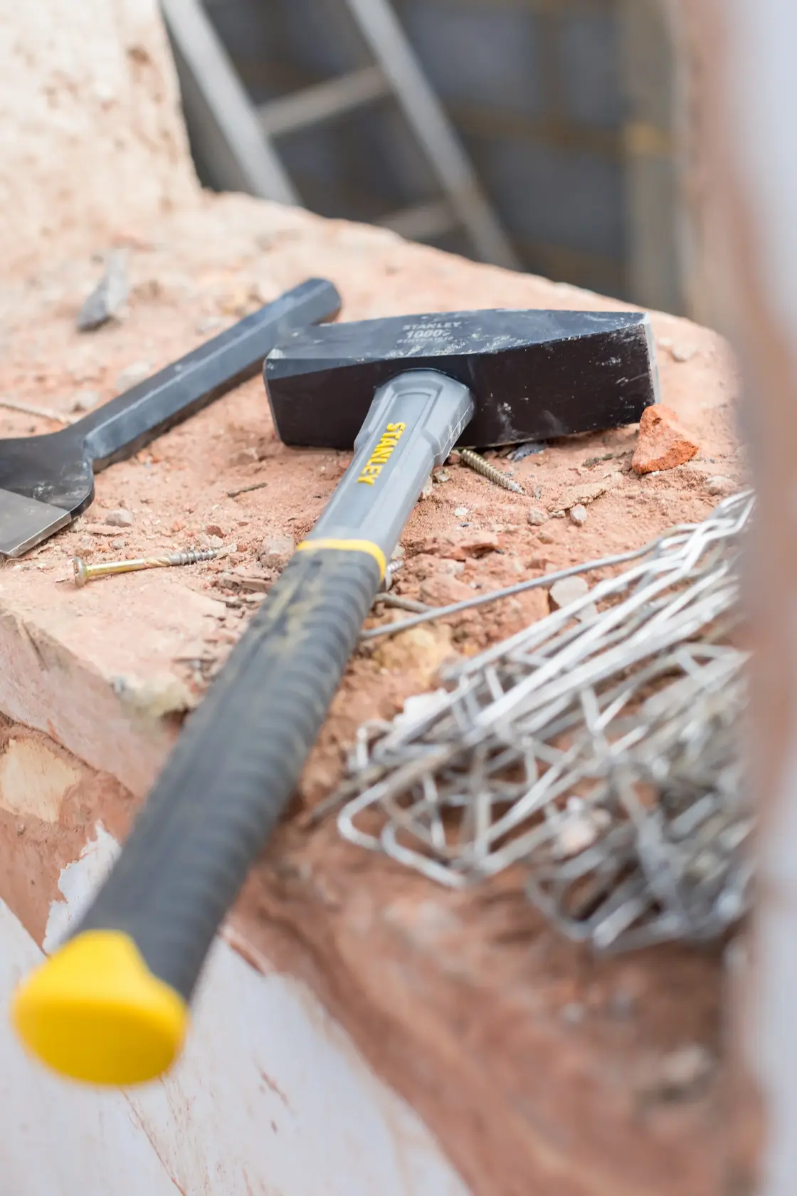 Mazzuolo STANLEY STHT0-51910 con testa nera e manico grigio-giallo in un cantiere.
