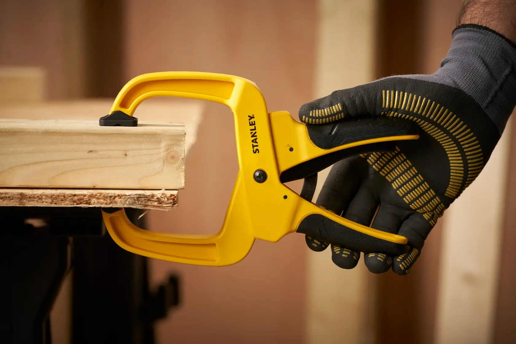 STANLEY STHT0-83200 morsetto che blocca assi di legno, mano con guanto in uso in officina.