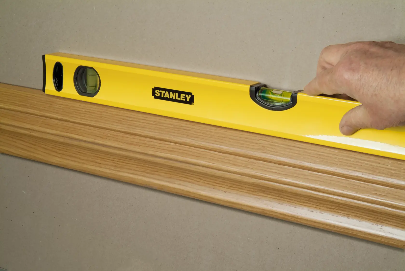 Livella STANLEY STHT1-43103 verifica l’allineamento su modanatura in legno, angolo laterale ravvicinato.