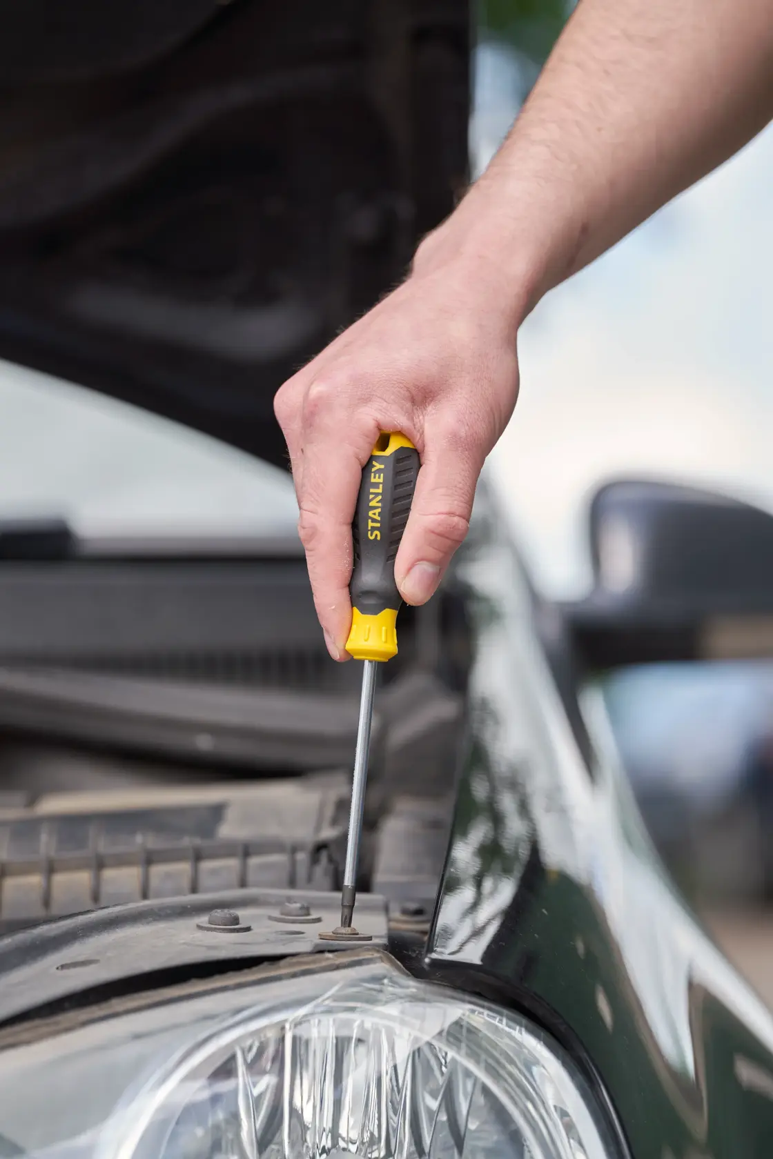 STANLEY STHT16179-0 cacciavite usato su motore auto, impugnatura ergonomica nera e gialla.