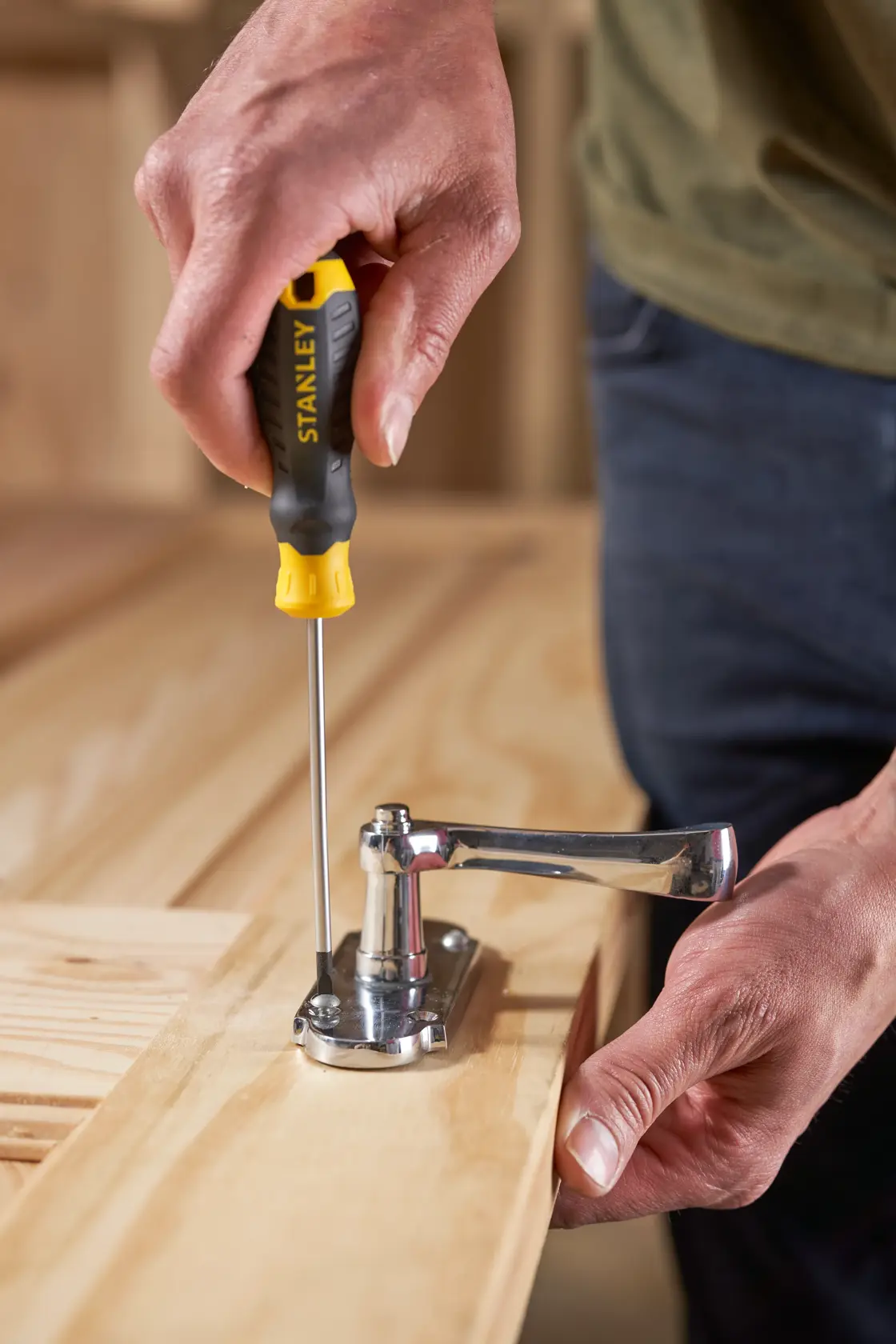 STANLEY STHT16195-0 cacciavite con manico nero e giallo utilizzato per fissare una cerniera su una superficie in legno.