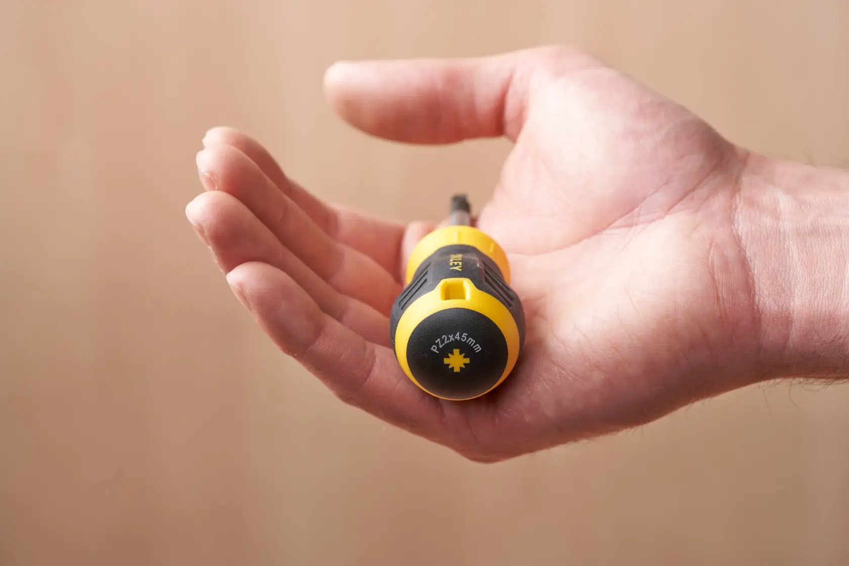 STANLEY STHT16196-0 cacciavite corto giallo e nero tenuto in una mano aperta, vista laterale.