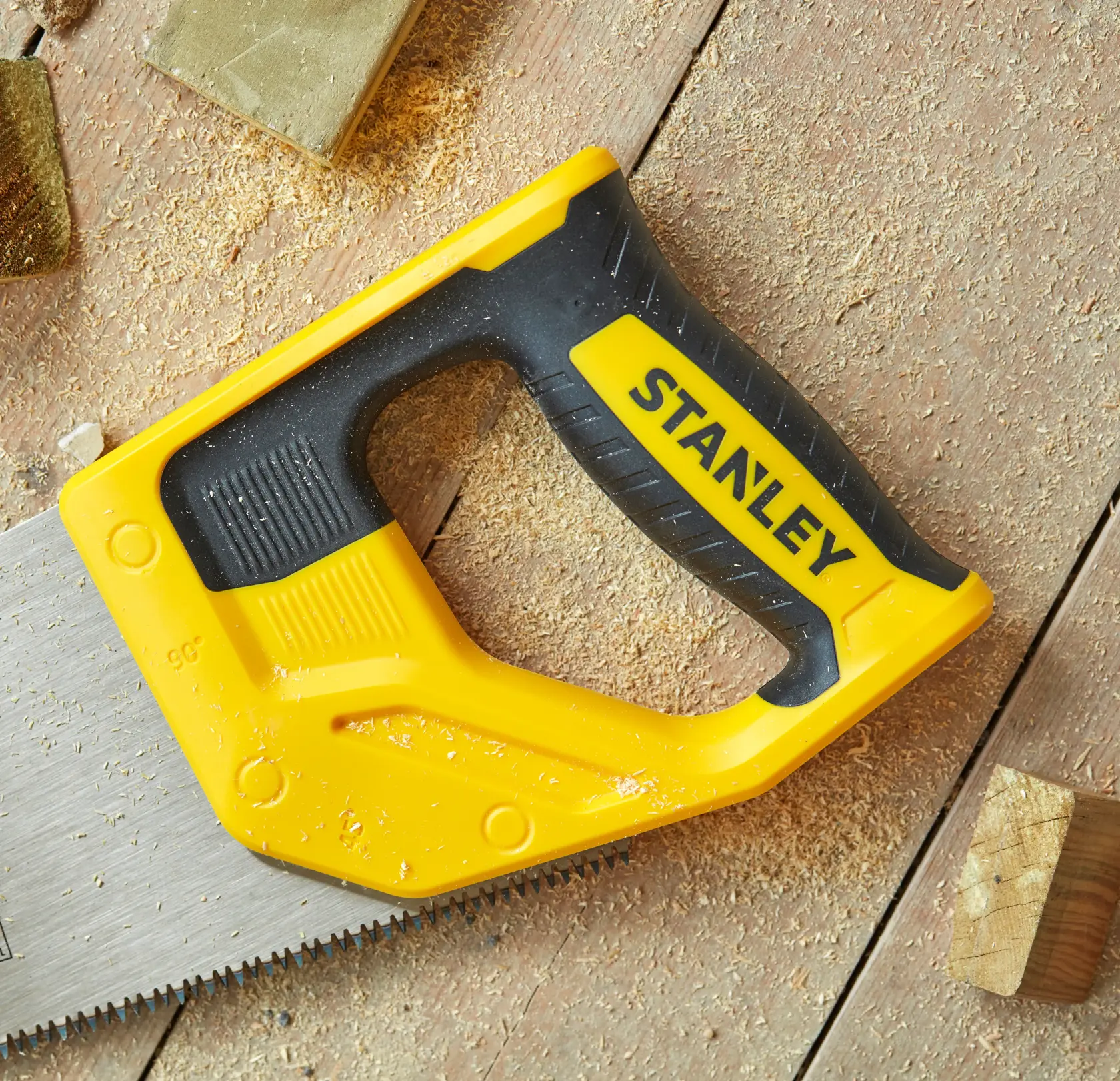 Foto del seghetto a mano STANLEY STHT20348-1 con manico giallo e nero su superficie in legno con segatura.