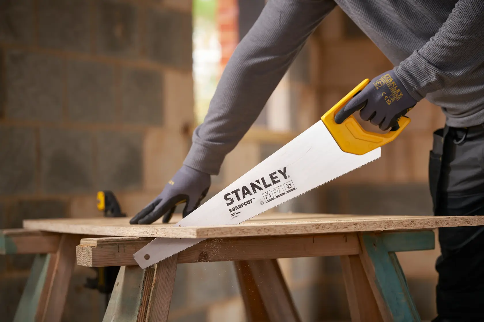 Foto del segaccio STANLEY STHT20368-1 con manico giallo che taglia legno in un cantiere.