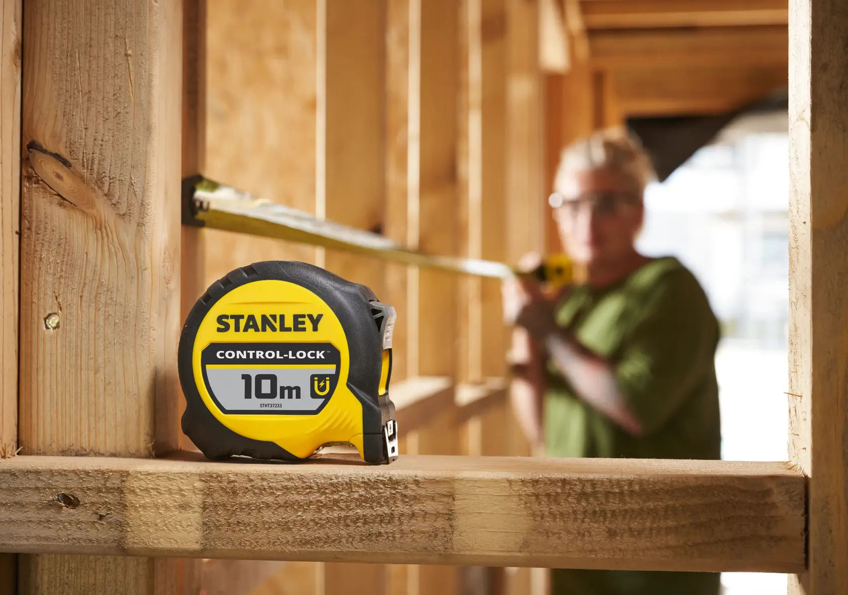 Stanley STHT37233-0 metro a nastro giallo e nero, 10m, mostrato su cantiere in legno.