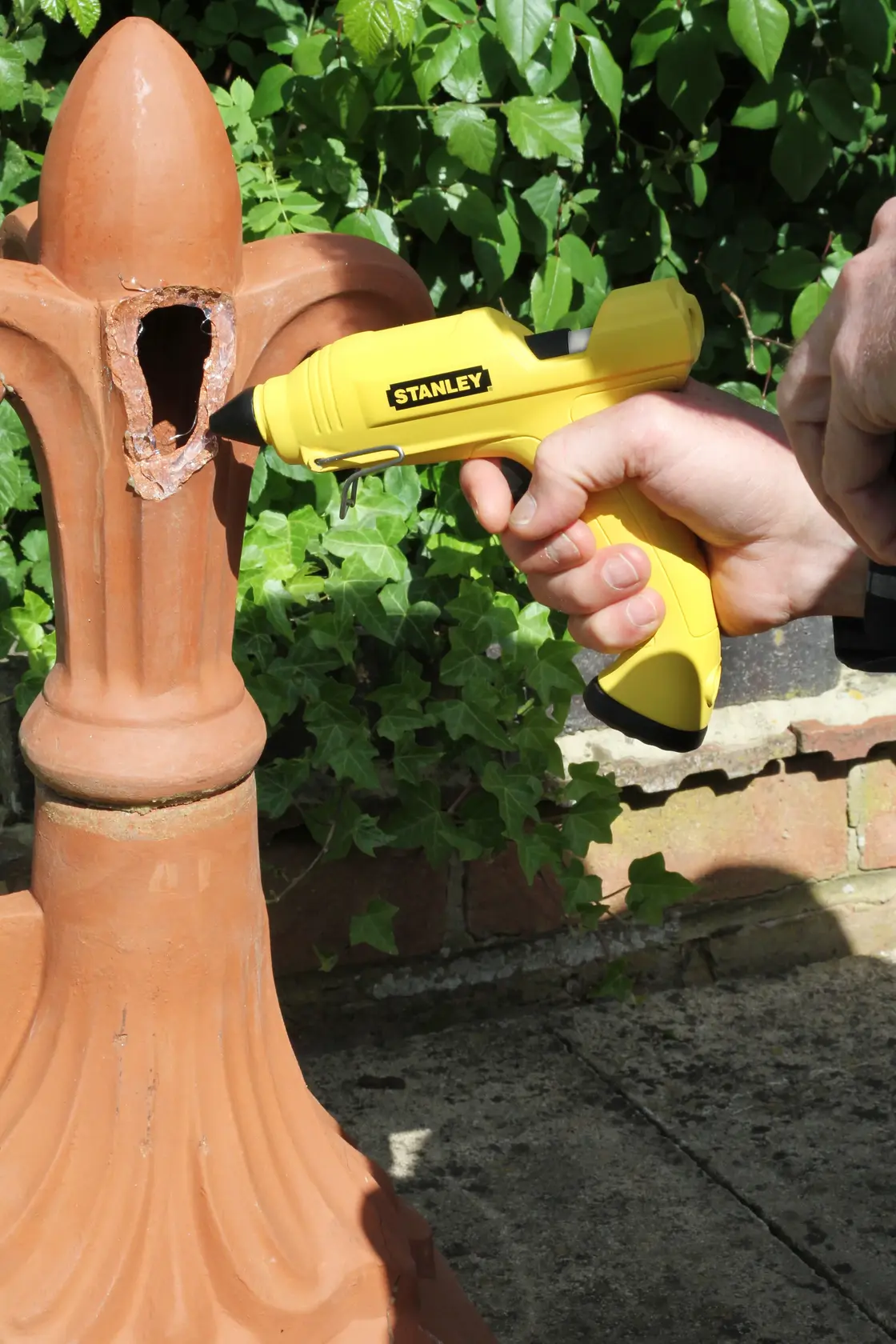 Stanley STHT6-70416 pistola per colla gialla utilizzata su terracotta danneggiata all'aperto.