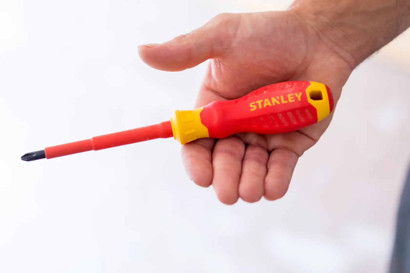 Foto di cacciavite isolato rosso e giallo STANLEY STHT60030-0 tenuto in mano.