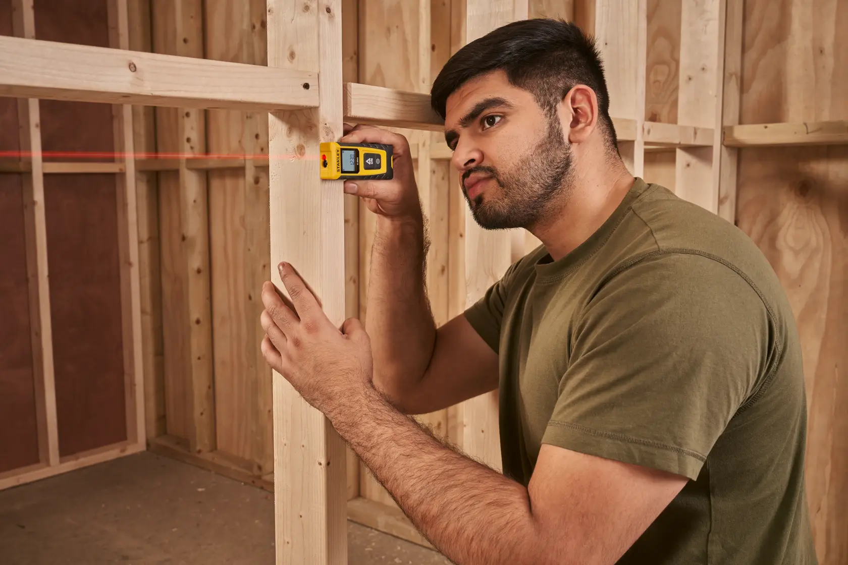 Foto del misuratore laser STANLEY STHT77065-0 in uso su un cantiere con telaio in legno.