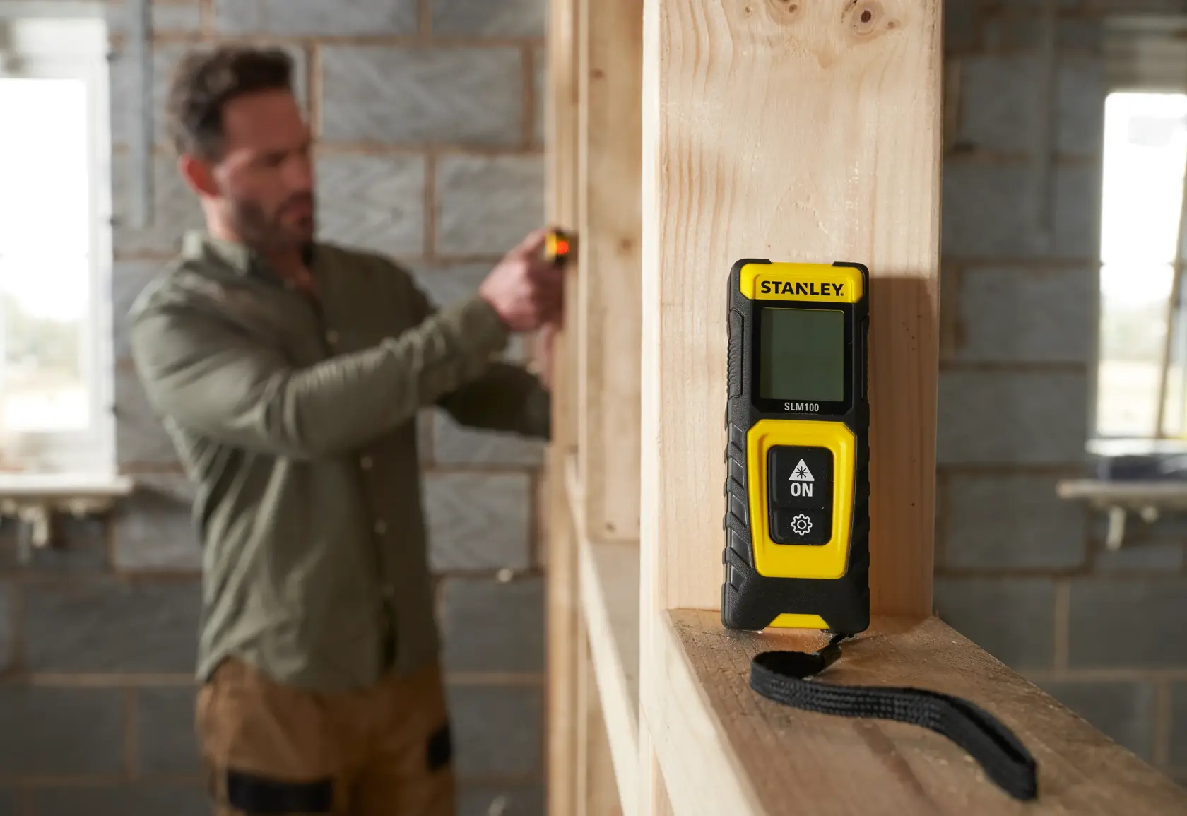 STANLEY STHT77100-0 misuratore laser nero e giallo su telaio in legno, scena di cantiere.