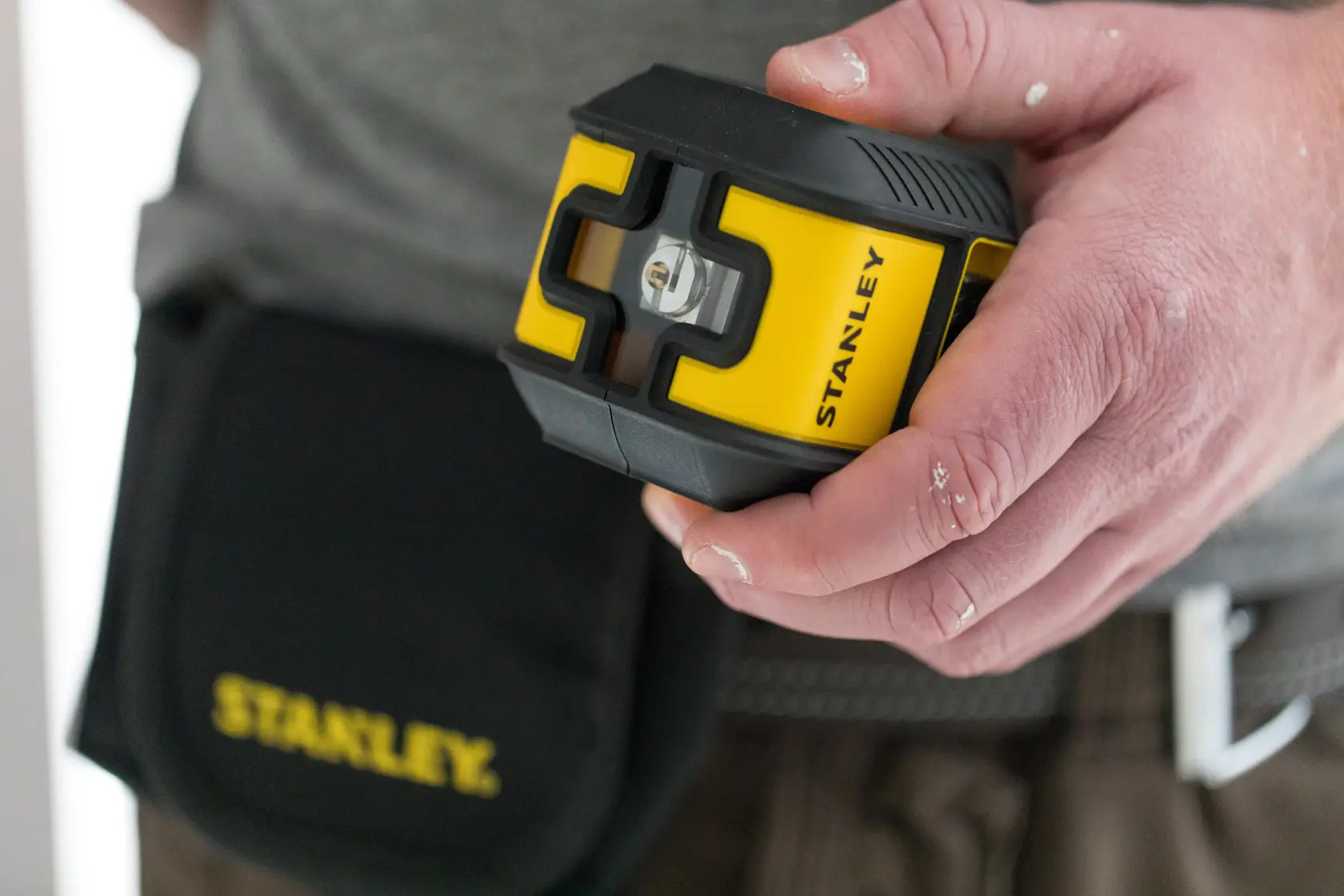 Foto del livello laser STANLEY STHT77499-1 giallo e nero tenuto in mano, custodia degli attrezzi visibile.