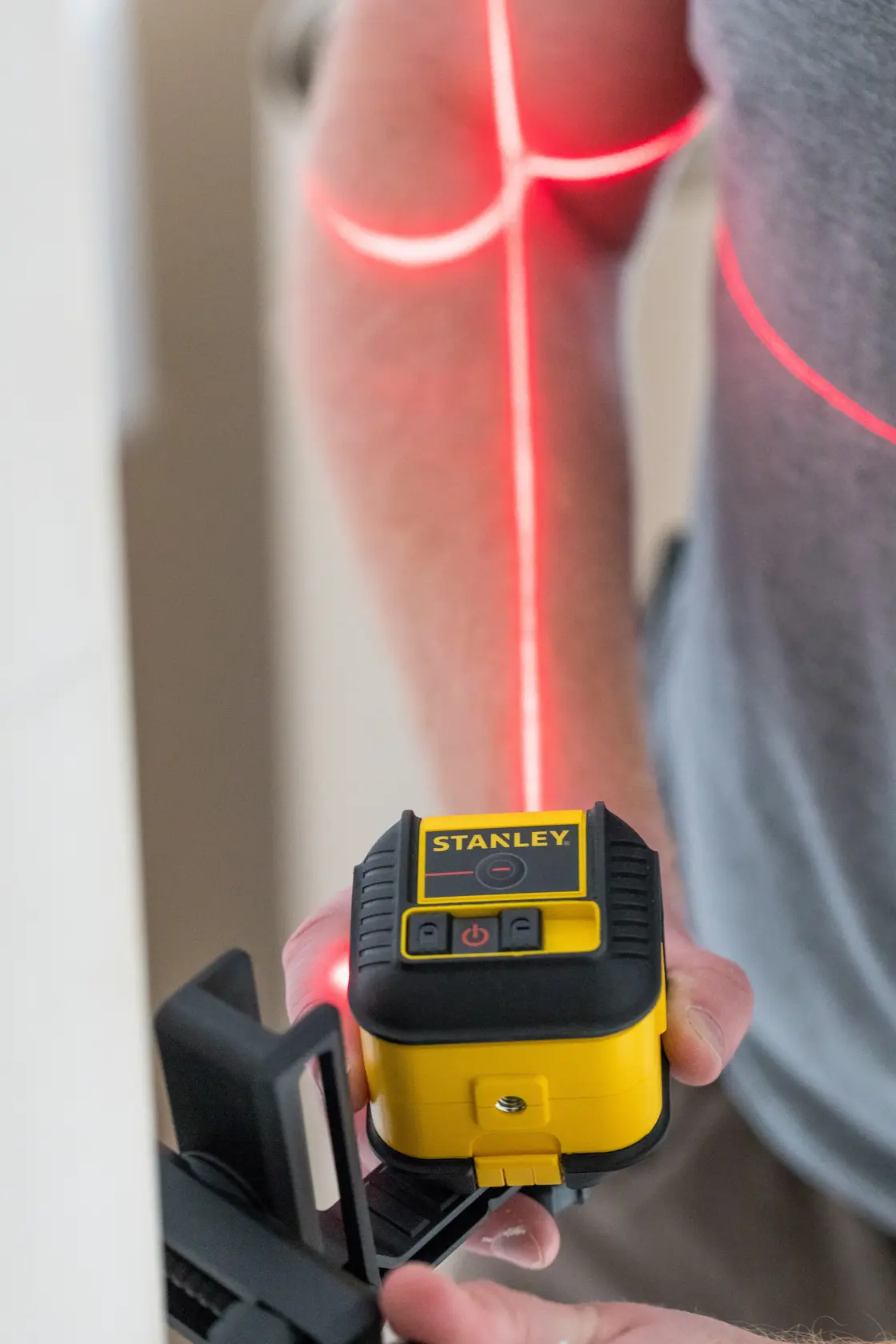 STANLEY STHT77502-1 livello laser a linee incrociate giallo e nero in uso che proietta linee laser rosse.