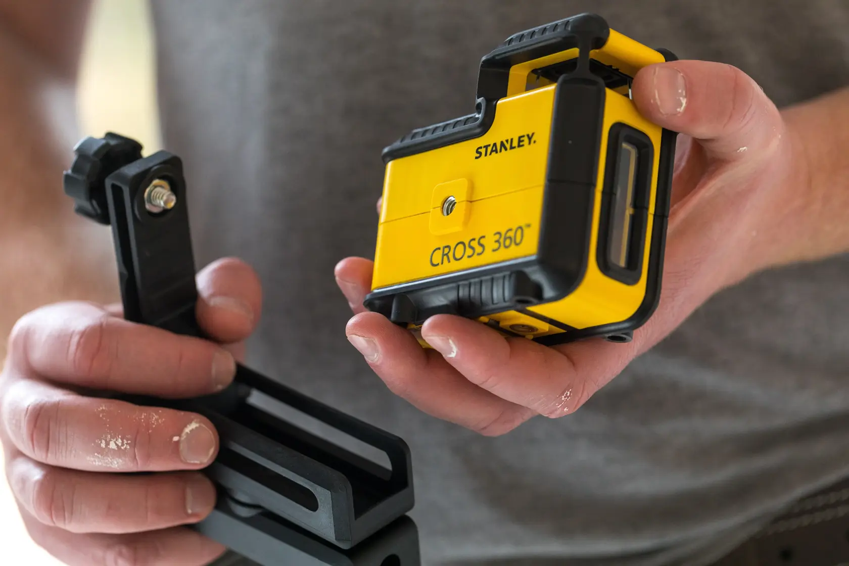 Foto del livello laser STANLEY STHT77504-1 CROSS 360 con staffa di montaggio, tenuto in mano.