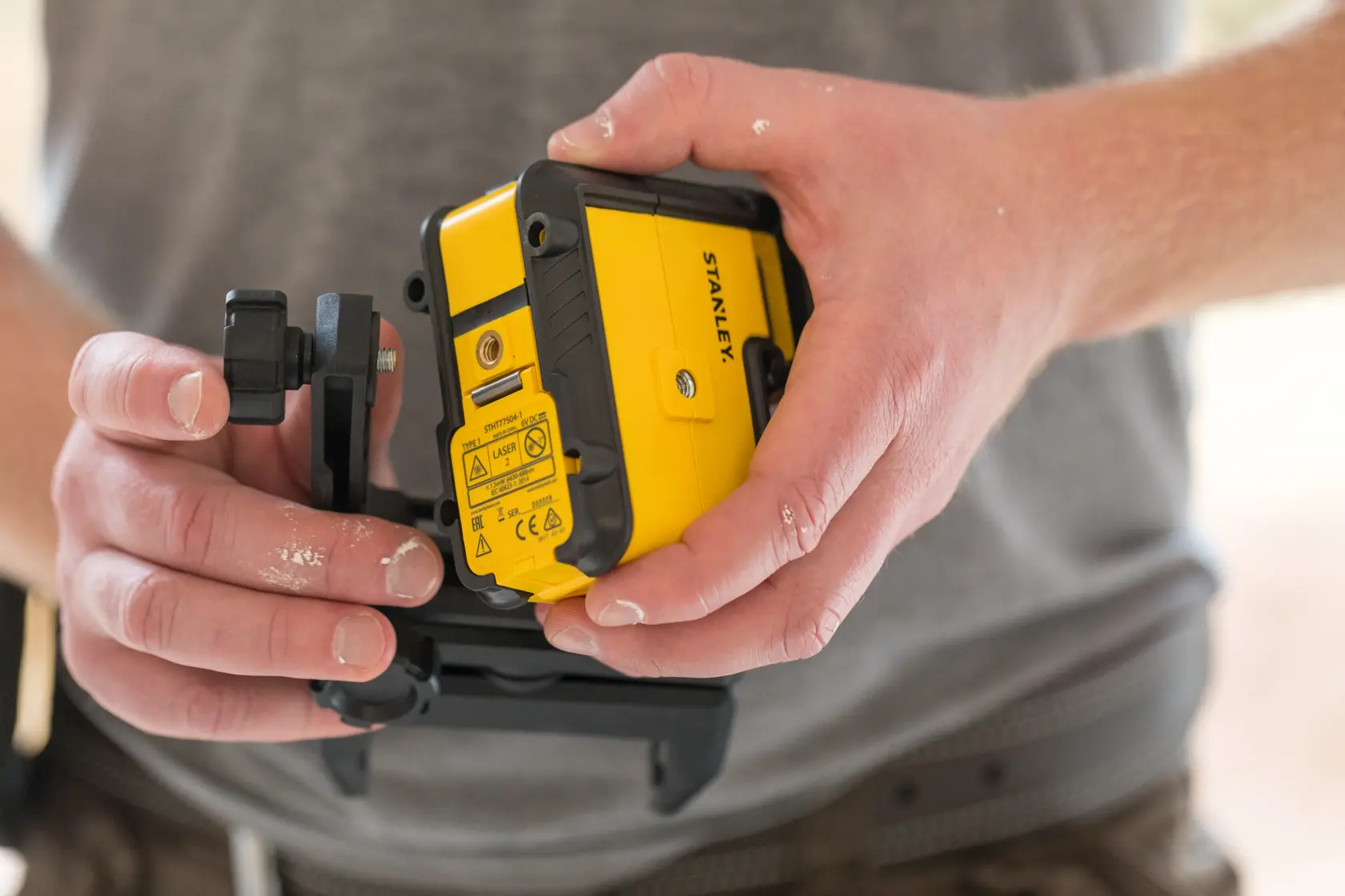 Foto del livello laser giallo e nero STANLEY STHT77504-1 tenuto in mano, contesto di costruzione.