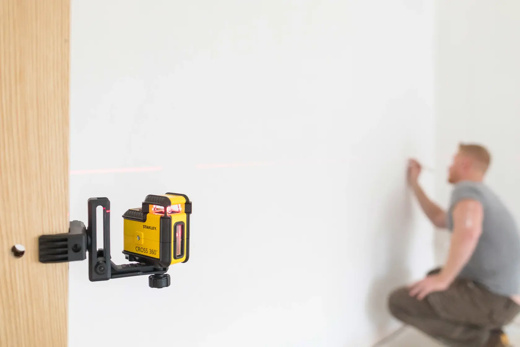 STANLEY STHT77504-1 dispositivo livello laser montato su legno, emette linea rossa, persona segna parete.
