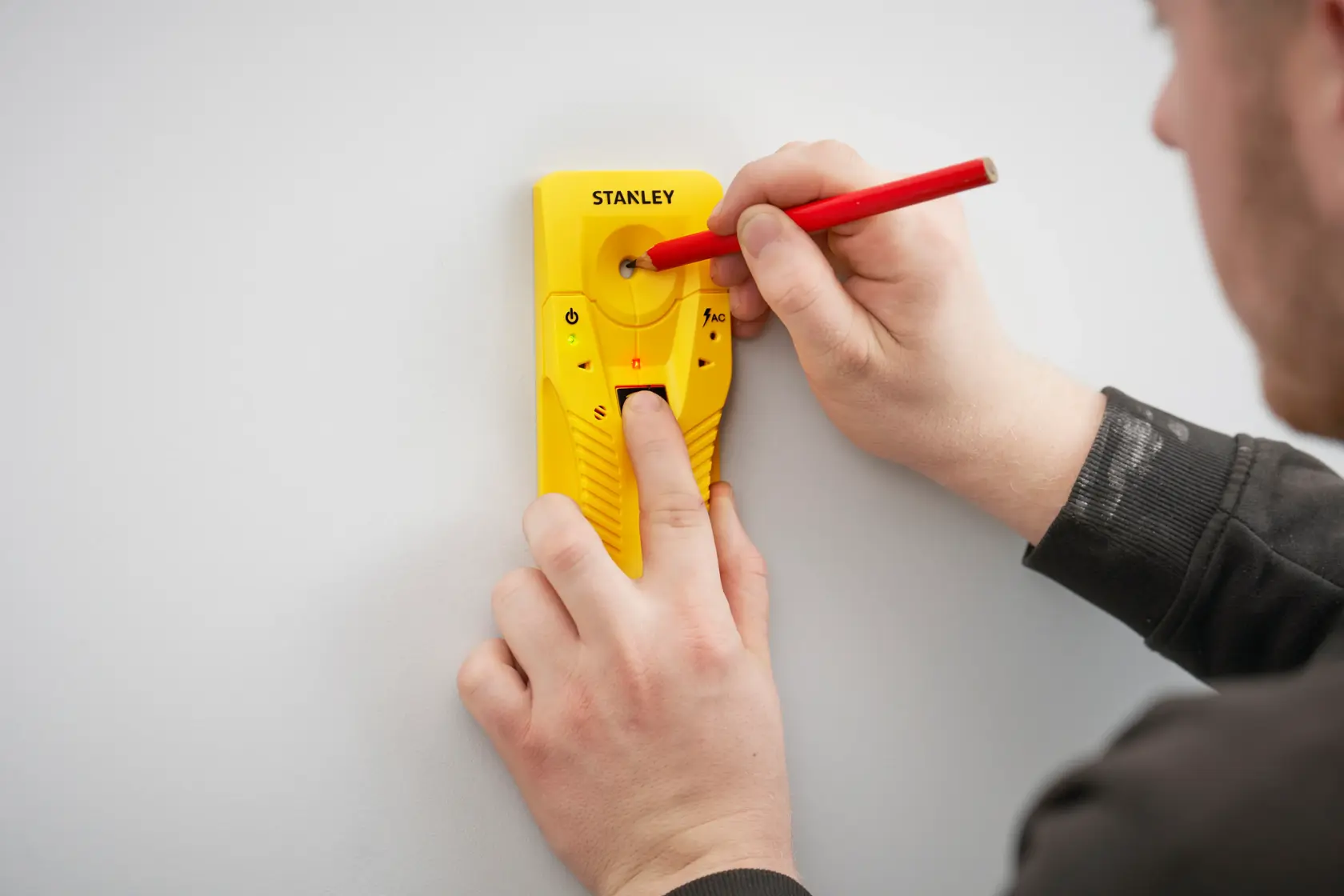STANLEY STHT77587-0 rilevatore di montanti giallo sulla parete, utente segna il punto con una matita rossa.