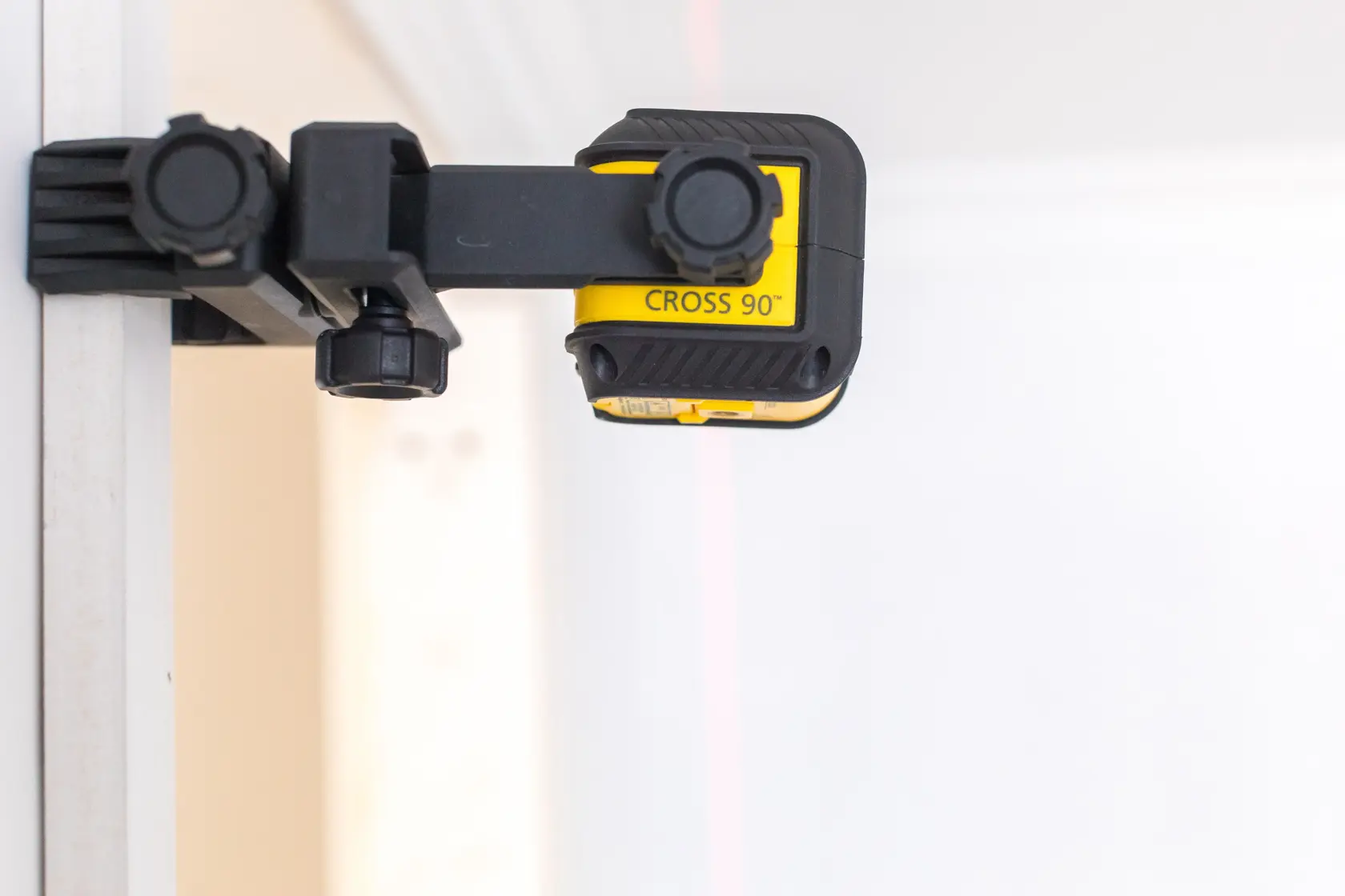 Livella laser a linee incrociate STANLEY STHT77592-1 montata su parete, vista laterale, corpo giallo e nero.