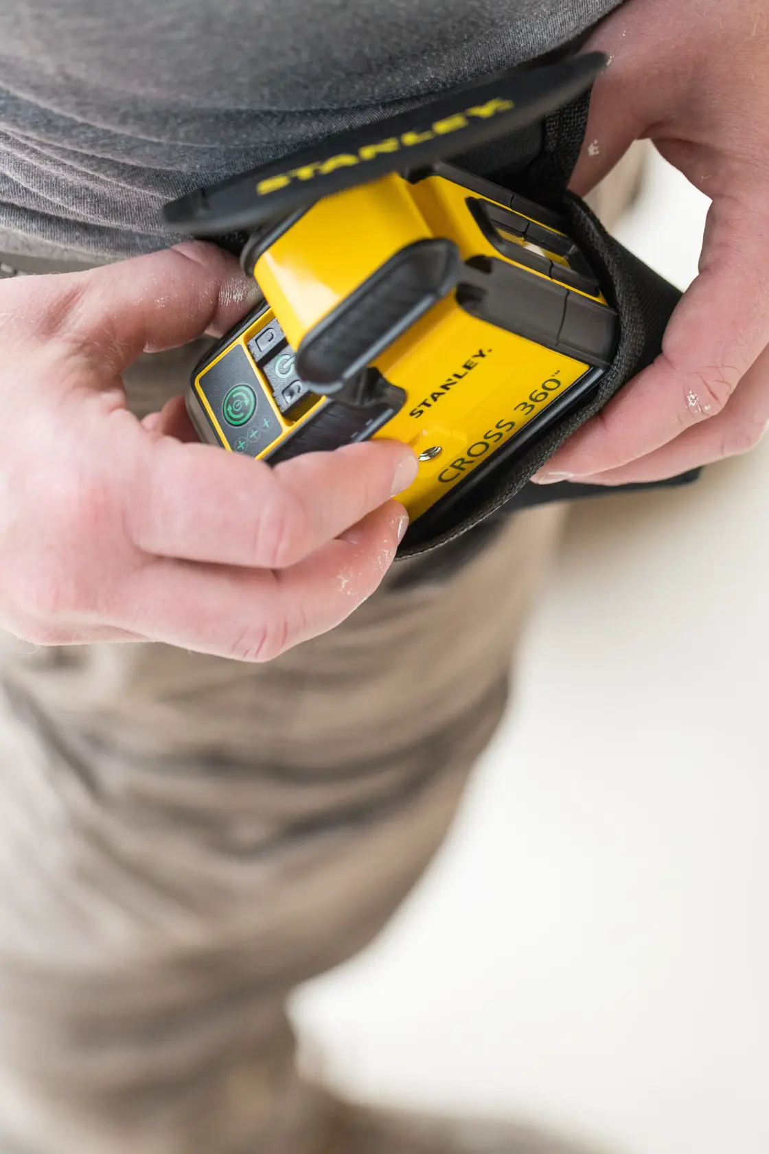 STANLEY STHT77594-1 livello laser giallo Cross 360 tenuto in mano con custodia protettiva.