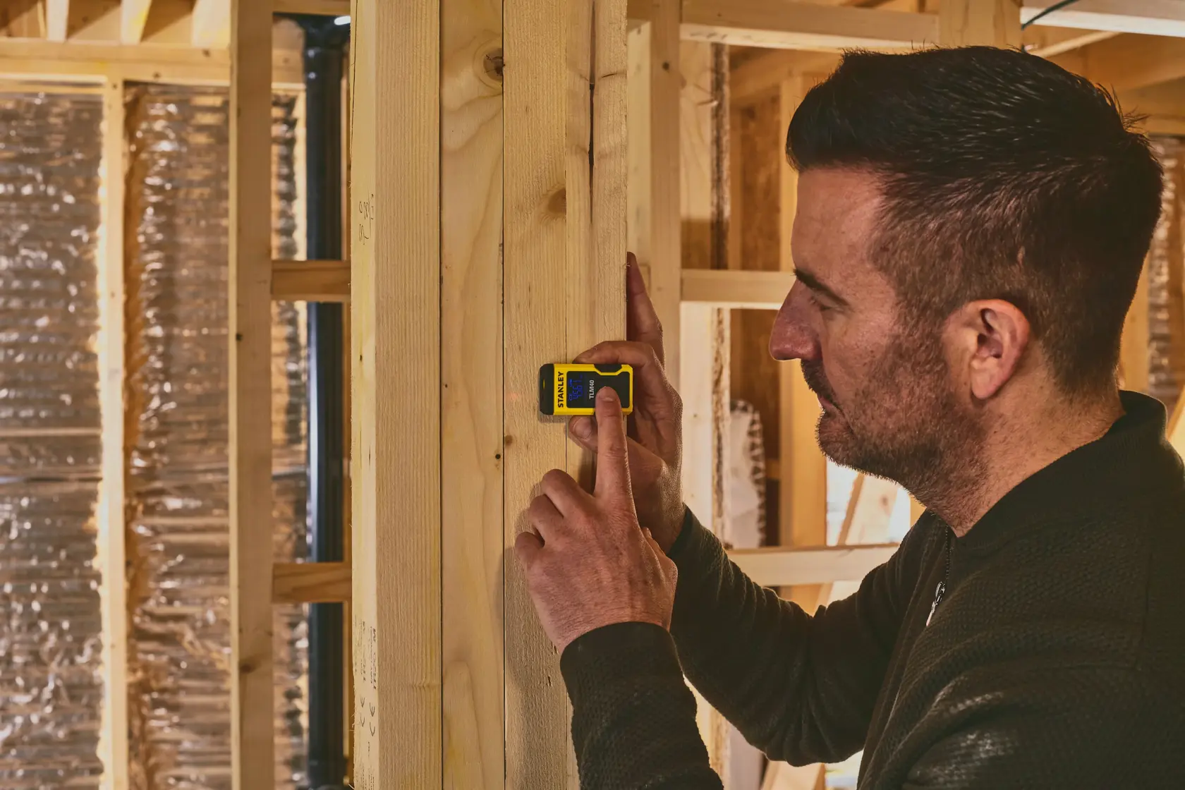 Distanziometro laser STANLEY STHT77666-0 in uso su trave di legno, ambiente di costruzione interna.