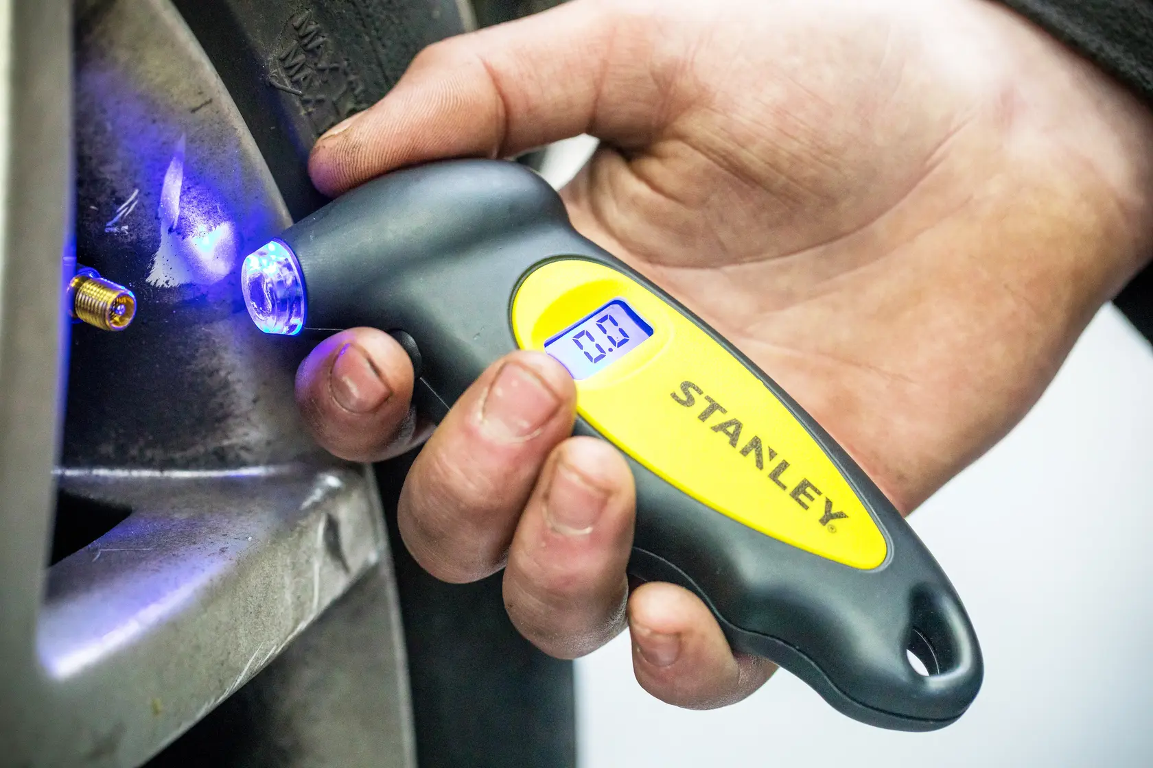 Stanley STHT80874-0 manometro digitale per pneumatici con LED blu, tenuto vicino alla valvola.