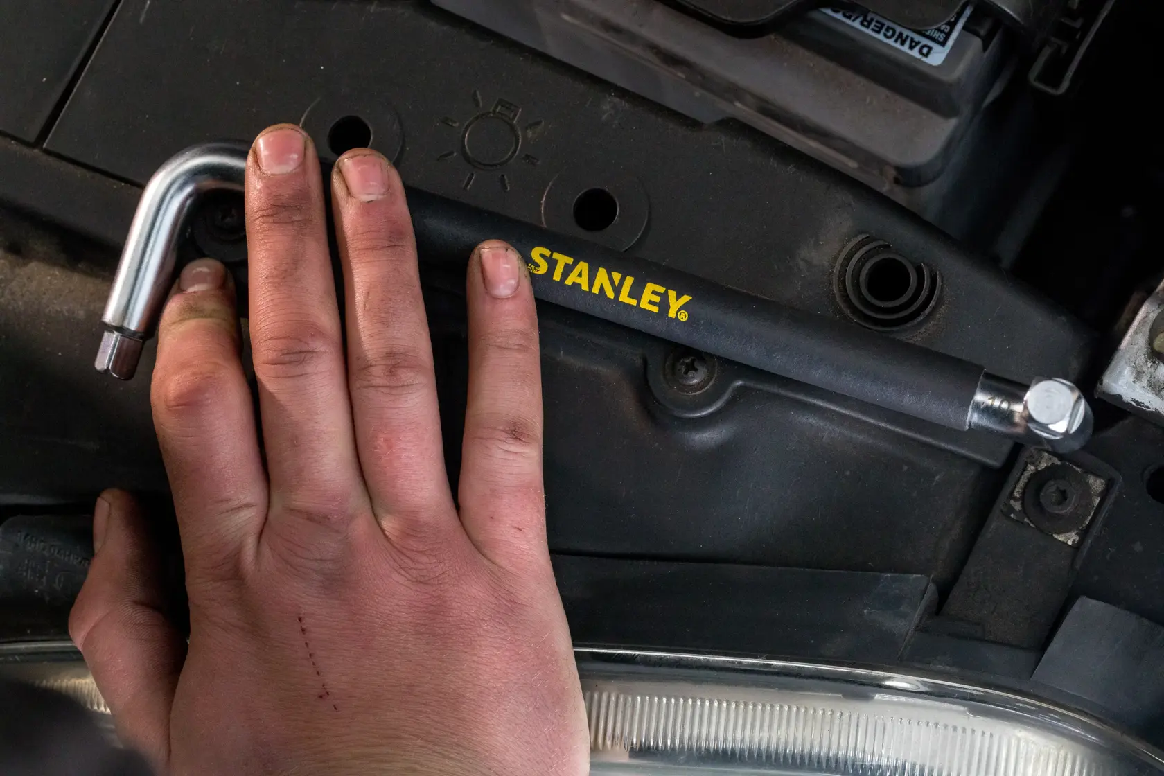 Foto dello strumento a L STANLEY STHT80879-0 tenuto da una mano in contesto motore auto.