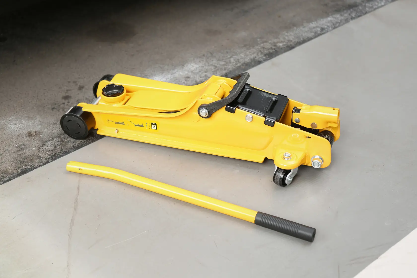 STANLEY STMT81251-1 cric idraulico da pavimento giallo con manico, vista laterale, su superficie di cemento.