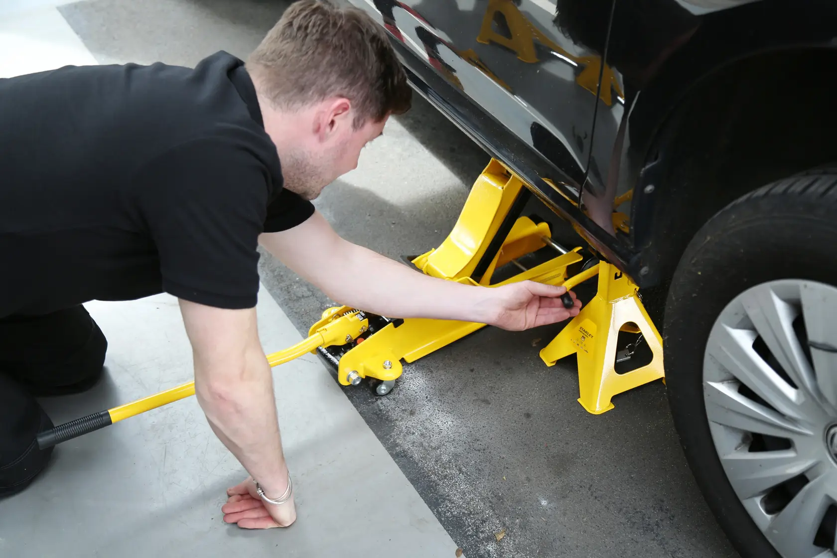 STANLEY STMT81255-1 cavalletto e cric giallo in uso sotto veicolo, vista laterale, accessorio automobilistico.