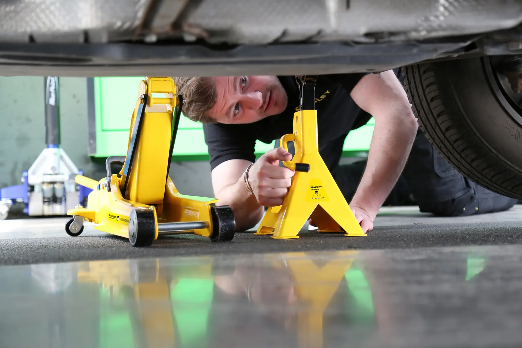 Foto di STANLEY STMT81255-1 cric e supporto gialli sotto veicolo, scena di utilizzo automotivo.