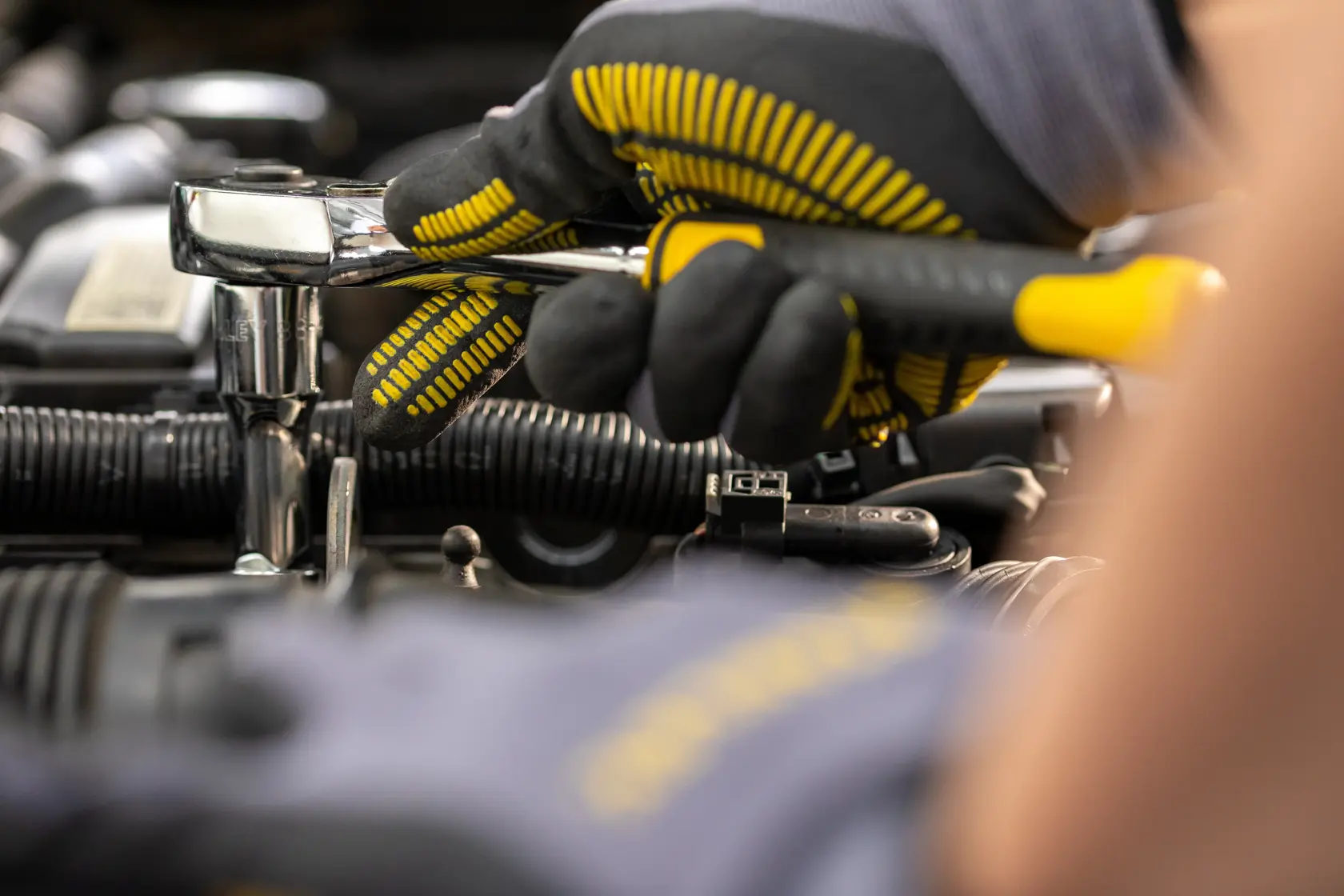 STANLEY STMT82665-0 chiave a cricchetto usata da mano con guanto su motore auto, foto close-up.
