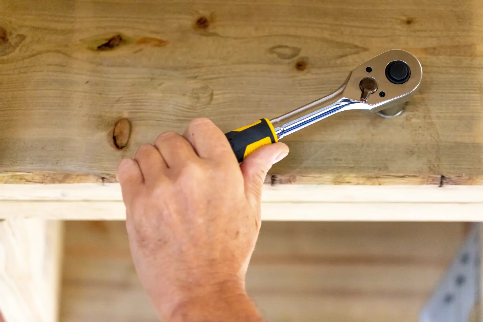 Cricchetto STANLEY STMT82665-0 utilizzato su legno, primo piano di una mano che tiene l’attrezzo.