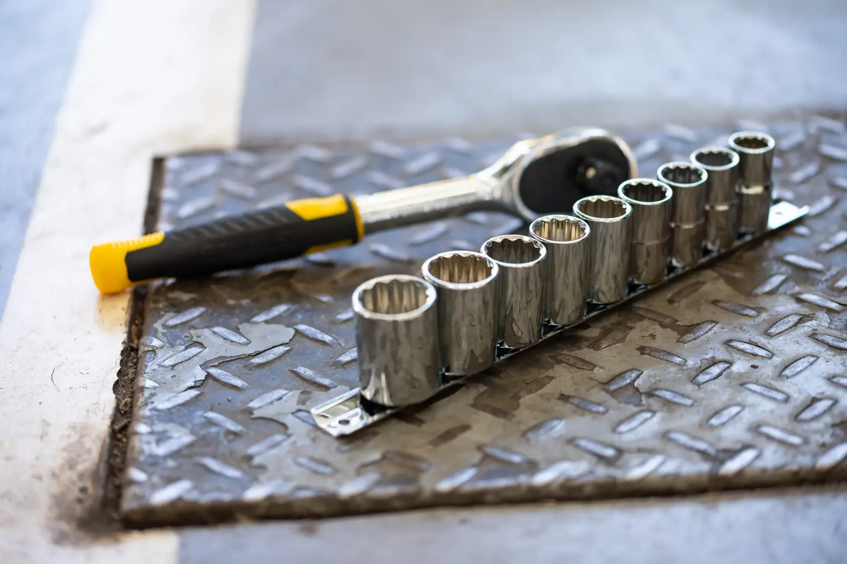 STANLEY STMT82666-0 chiave a cricchetto e set di nove bussole su pavimento metallico, vista angolata.