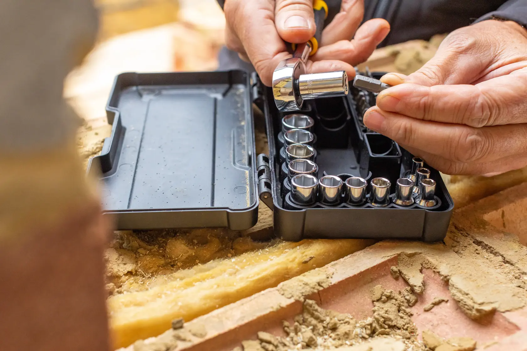 Set di bussole STANLEY STMT82672-0 con cricchetto in valigetta nera su cantiere, mani scelgono una bussola.