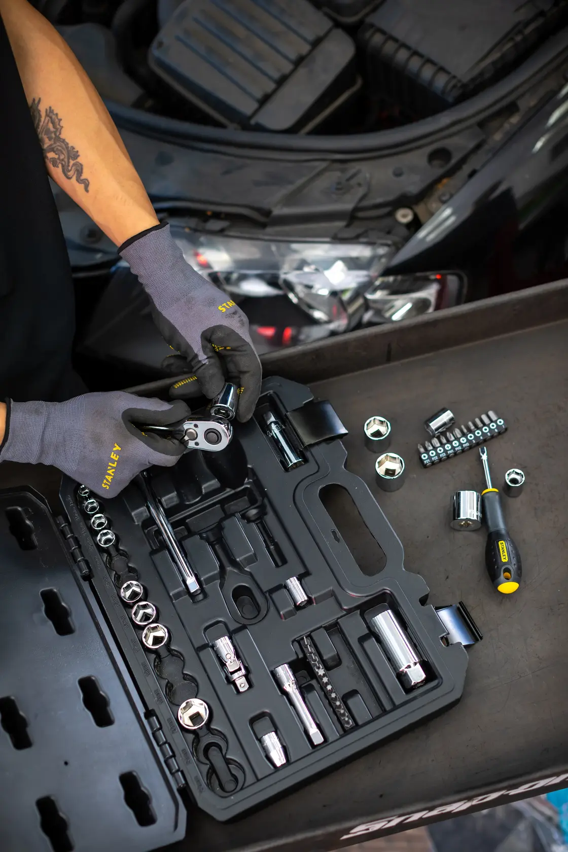 STANLEY STMT82829-1 set di bussole con cricchetto e cacciavite, aperto da meccanico vicino al motore dell’auto.